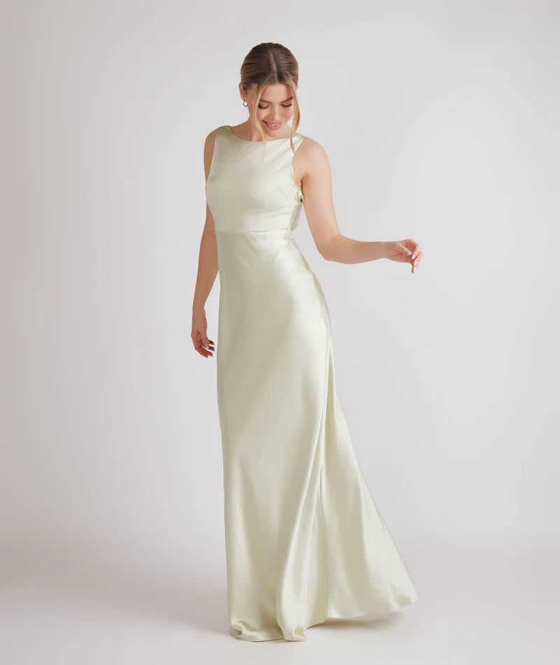 Woman wearing a long, pastel green satin dress on a white background
