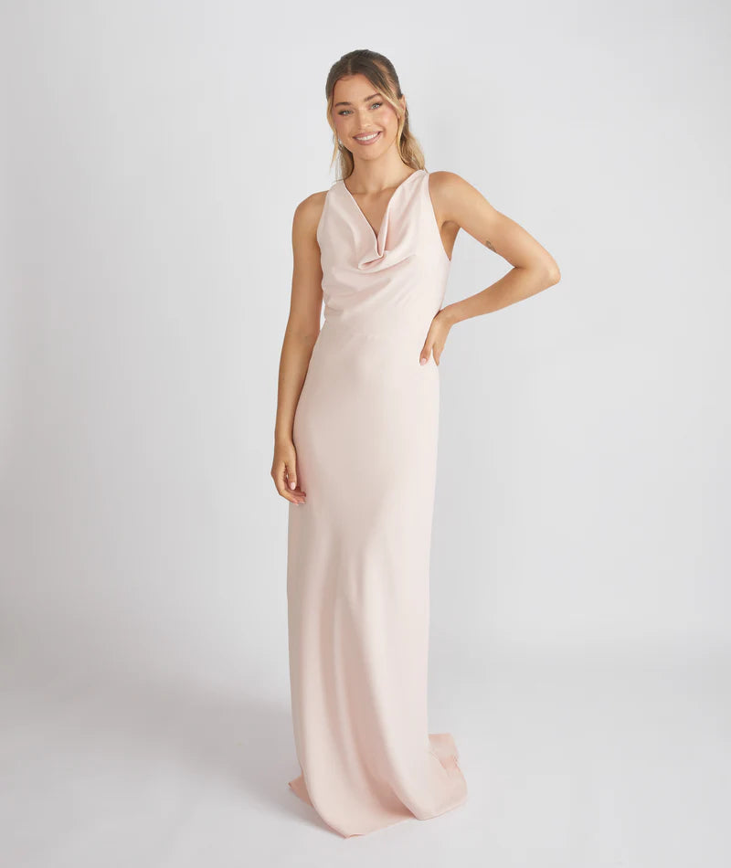 Woman wearing a long, light pink dress against a white background