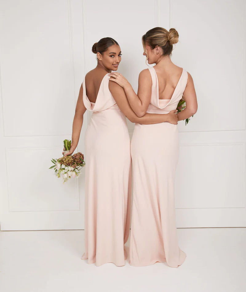 Two girls wearing soft pink bridesmaid dresses with cowl back by six stories