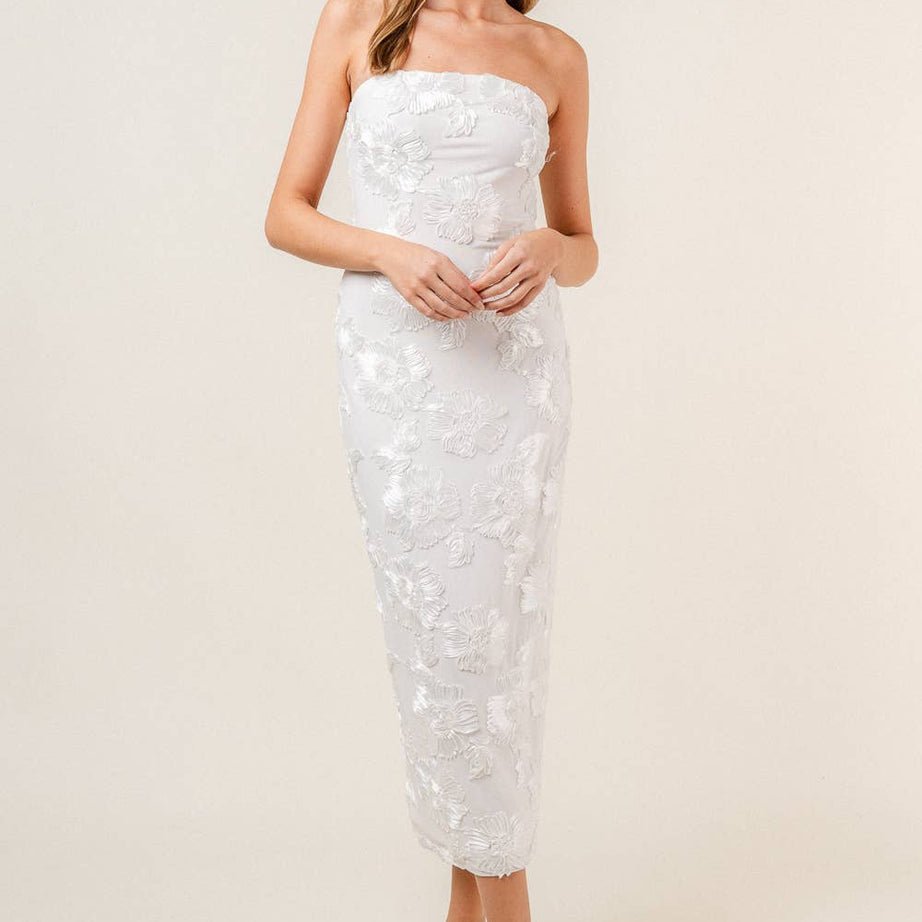Woman wearing a strapless white floral midi dress on a plain background