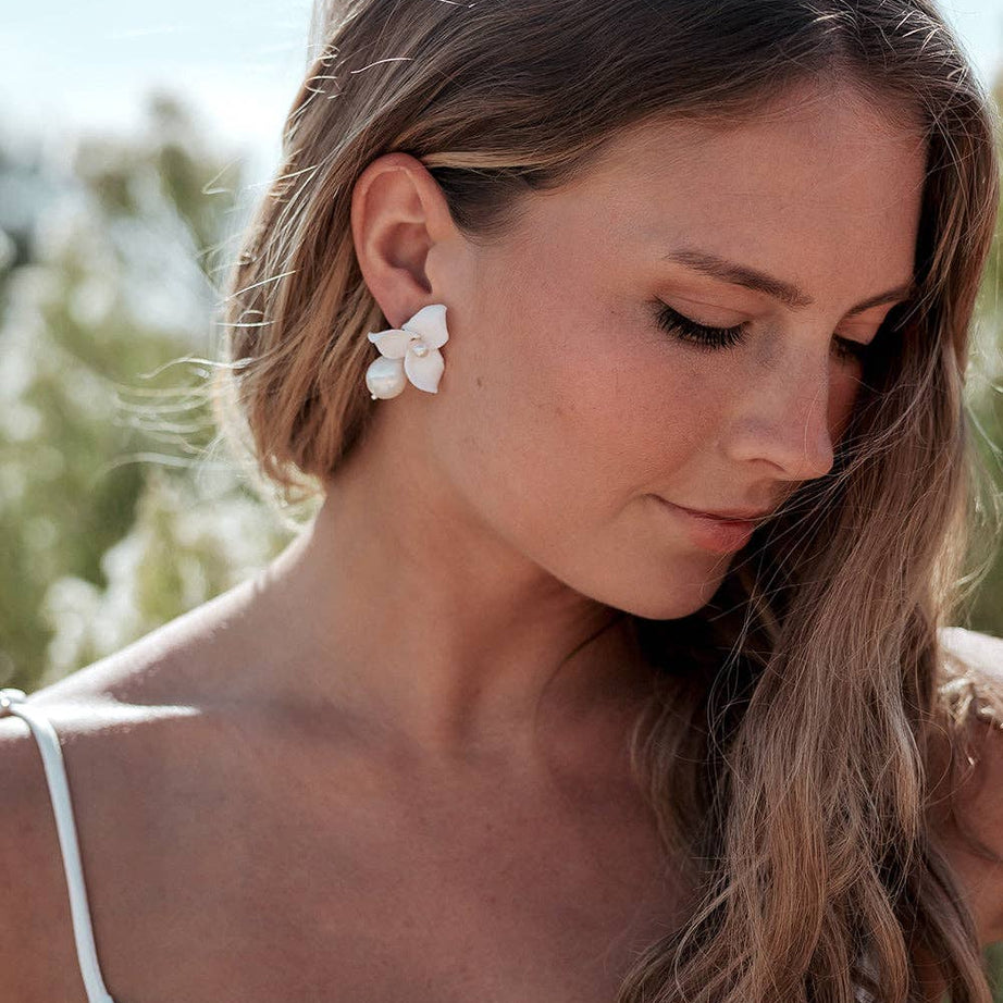 Make a statement of timeless sophistication on your wedding day with the Laurel Pearl Drop Earrings — a striking blend of modern design and classic beauty. Thoughtfully handcrafted, these earrings feature delicate ivory clay flowers paired with a luminous pear-shaped pearl that adds effortless refinement to any bridal or special occasion look.