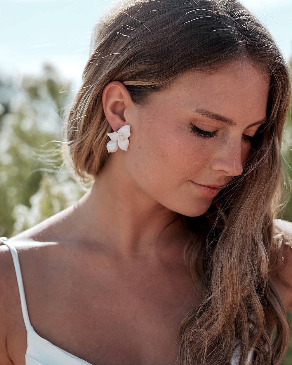 Make a statement of timeless sophistication on your wedding day with the Laurel Pearl Drop Earrings — a striking blend of modern design and classic beauty. Thoughtfully handcrafted, these earrings feature delicate ivory clay flowers paired with a luminous pear-shaped pearl that adds effortless refinement to any bridal or special occasion look.