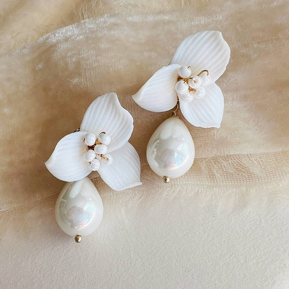 Make a statement of timeless sophistication on your wedding day with the Laurel Pearl Drop Earrings — a striking blend of modern design and classic beauty. Thoughtfully handcrafted, these earrings feature delicate ivory clay flowers paired with a luminous pear-shaped pearl that adds effortless refinement to any bridal or special occasion look.