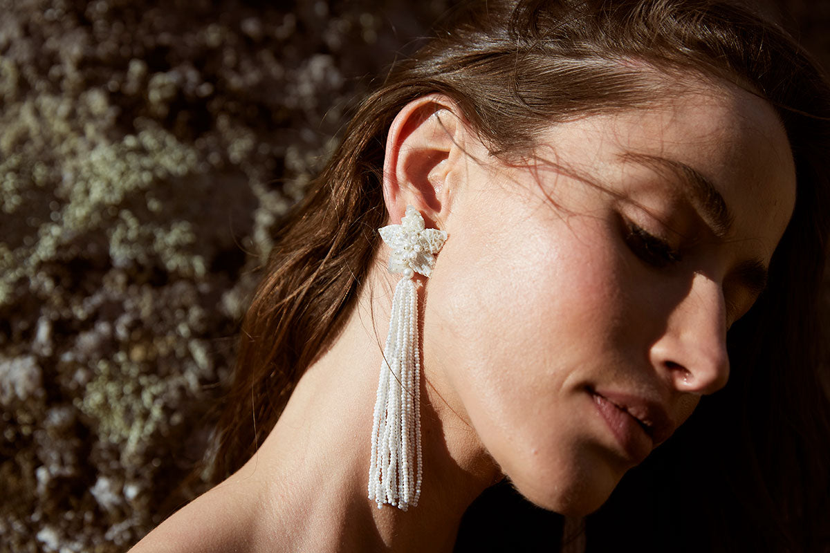 Lady wearing a long star shaped ivory beaded tassel earring.