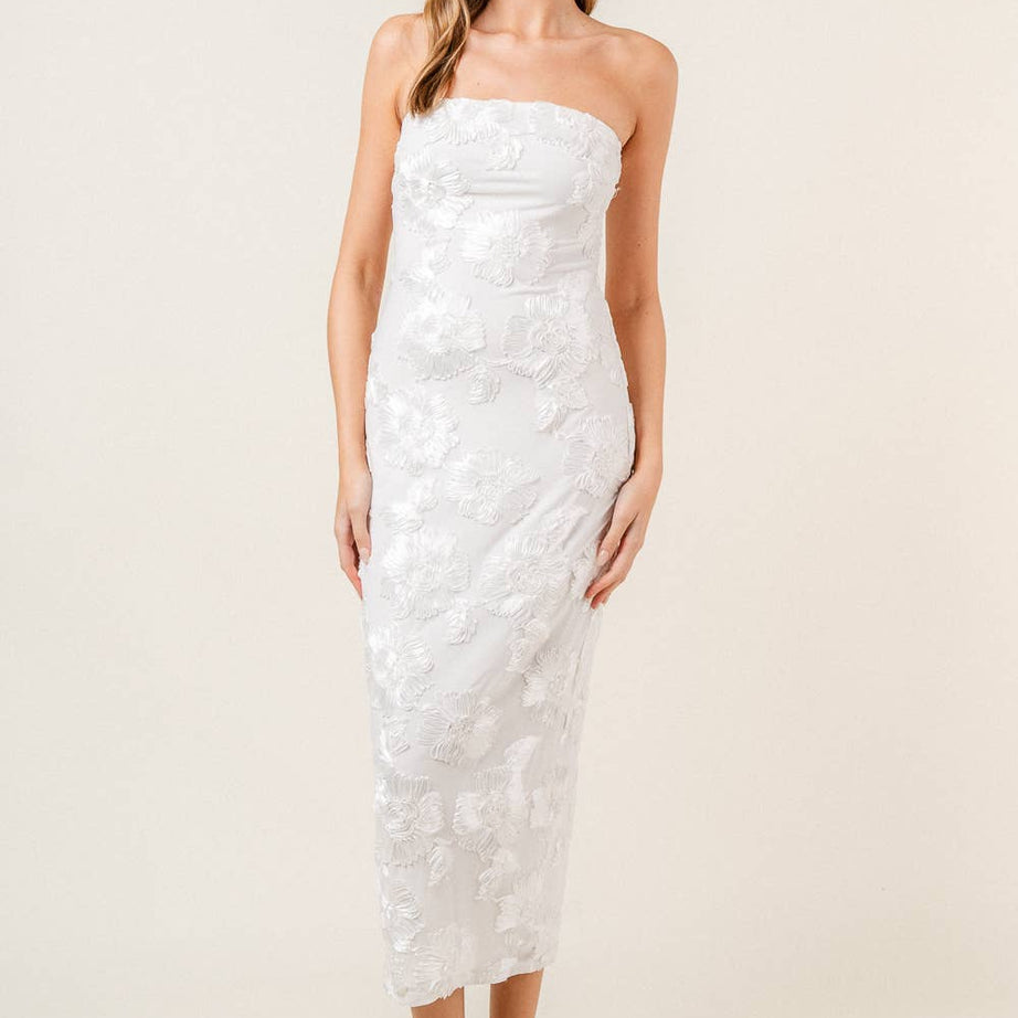 Woman wearing a strapless white floral midi dress on a plain background