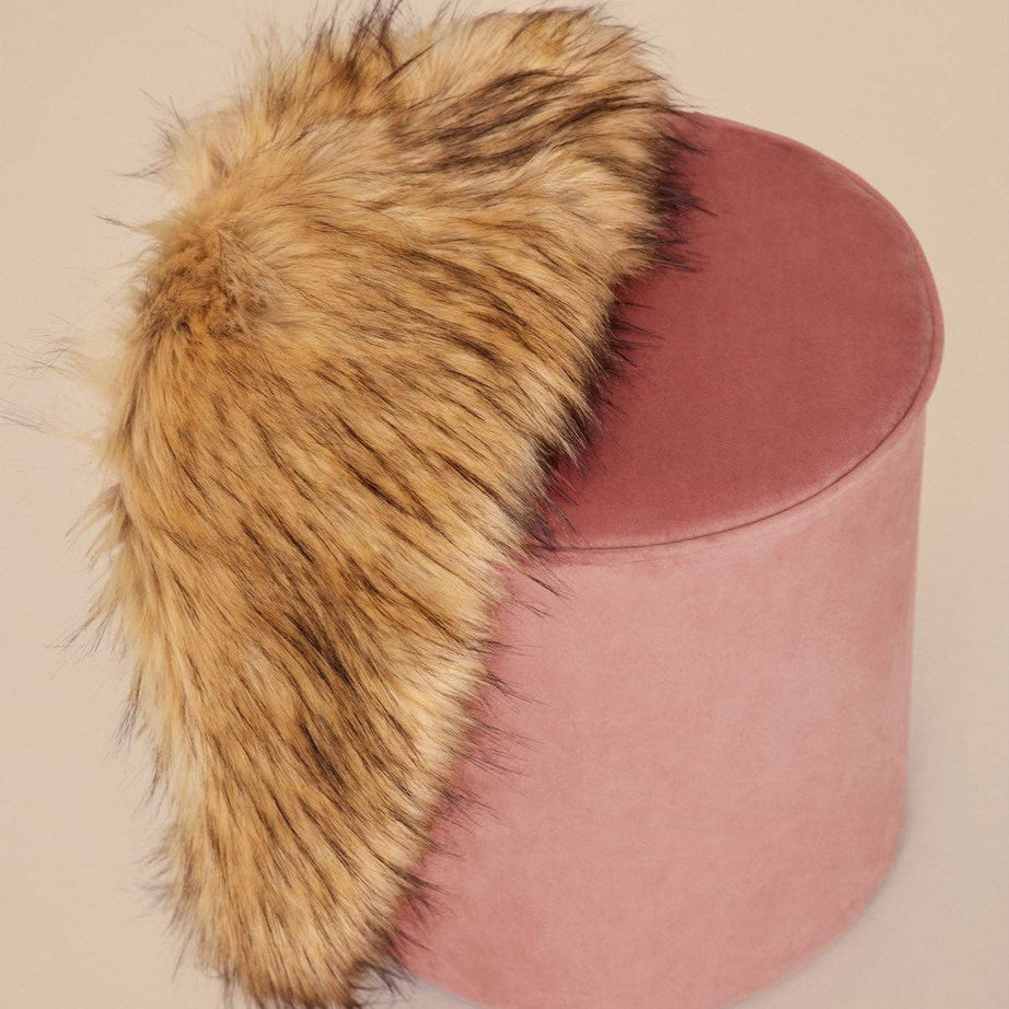 Natural faux fur stole on a pink velvet pouf