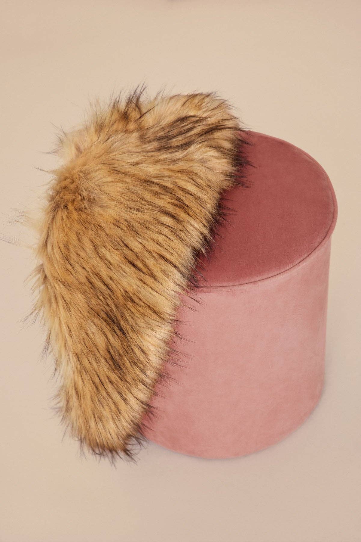 Natural faux fur stole on a pink velvet pouf