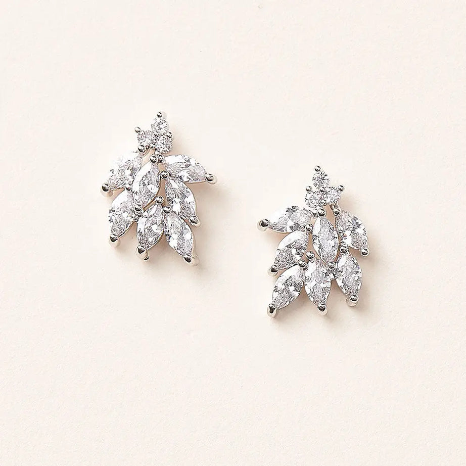 Pair of diamond leaf-shaped stud earrings on a light pink background