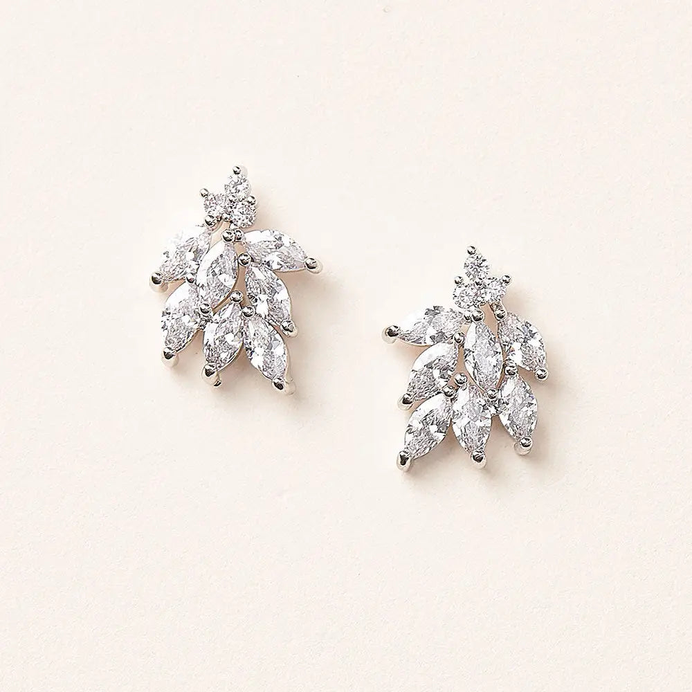 Pair of diamond leaf-shaped stud earrings on a light pink background