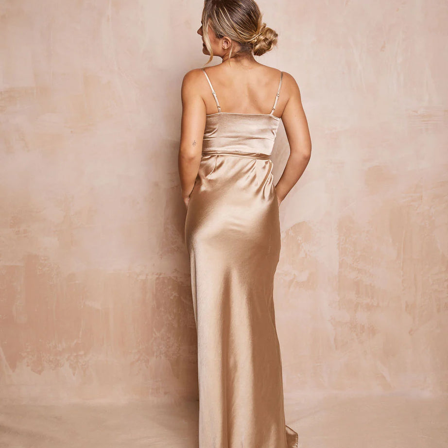 Woman wearing a long, light-colored satin dress against a matching background