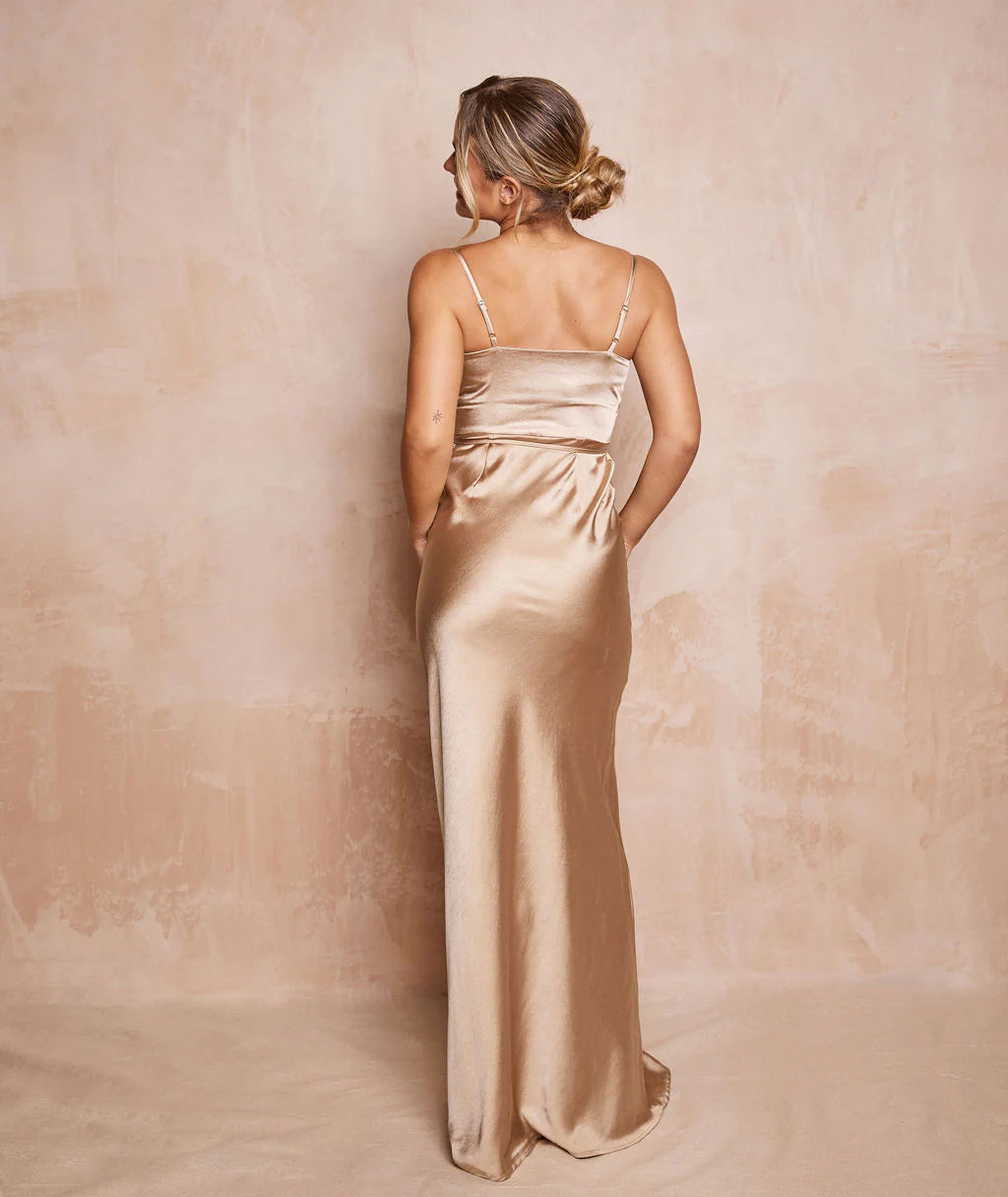 Woman wearing a long, light-colored satin dress against a matching background