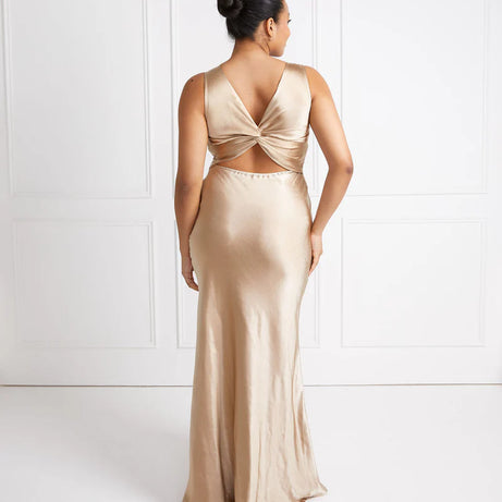 Woman wearing a gold bridesmaid evening gown with a white background
