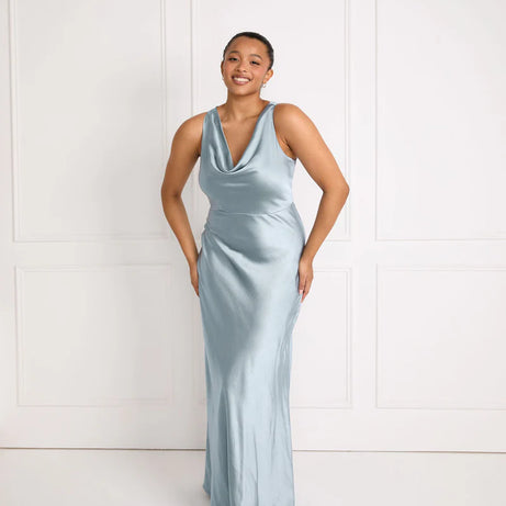 Woman wearing a light blue satin bridesmaid dress against a white background