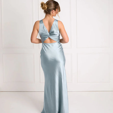 Woman wearing a light blue satin gown with a backless design against a white background