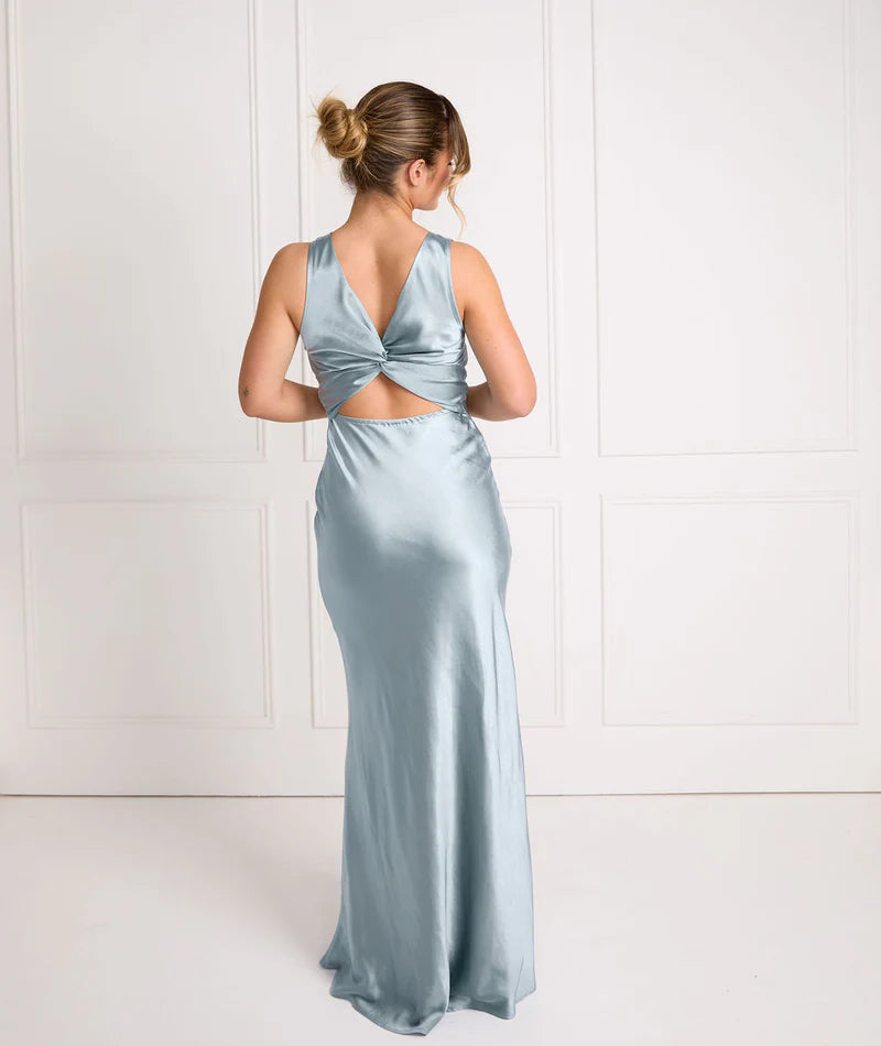 Woman wearing a light blue satin gown with a backless design against a white background