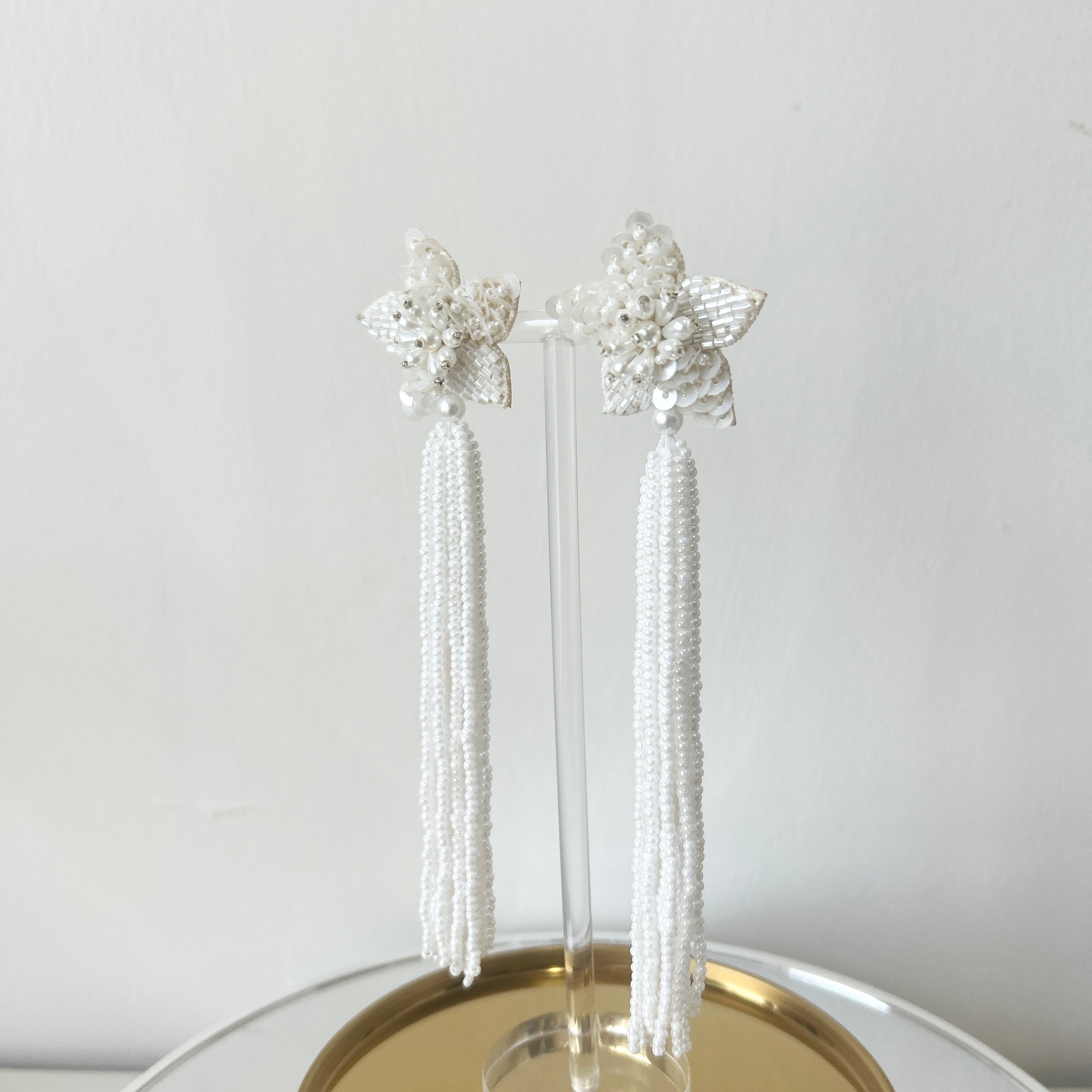 Image of long star shaped ivory beaded tassel earrings against a white backdrop.