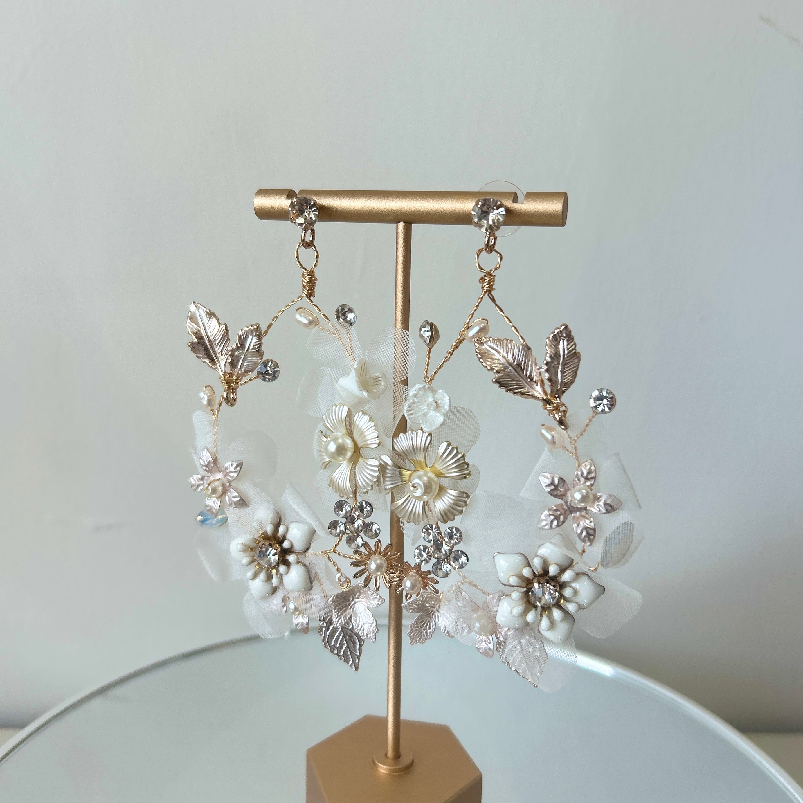 Pair of floral earrings on a gold stand against a light background