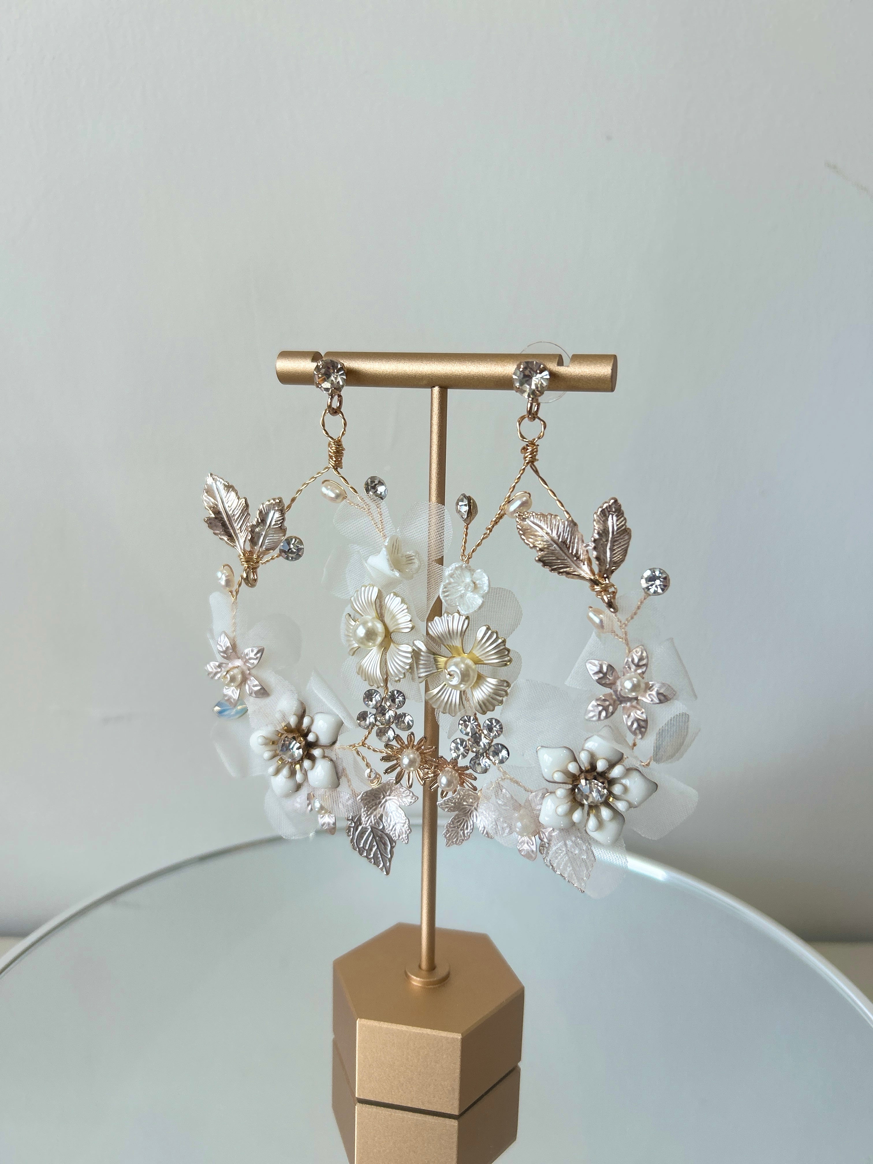 Pair of floral earrings on a gold stand against a light background