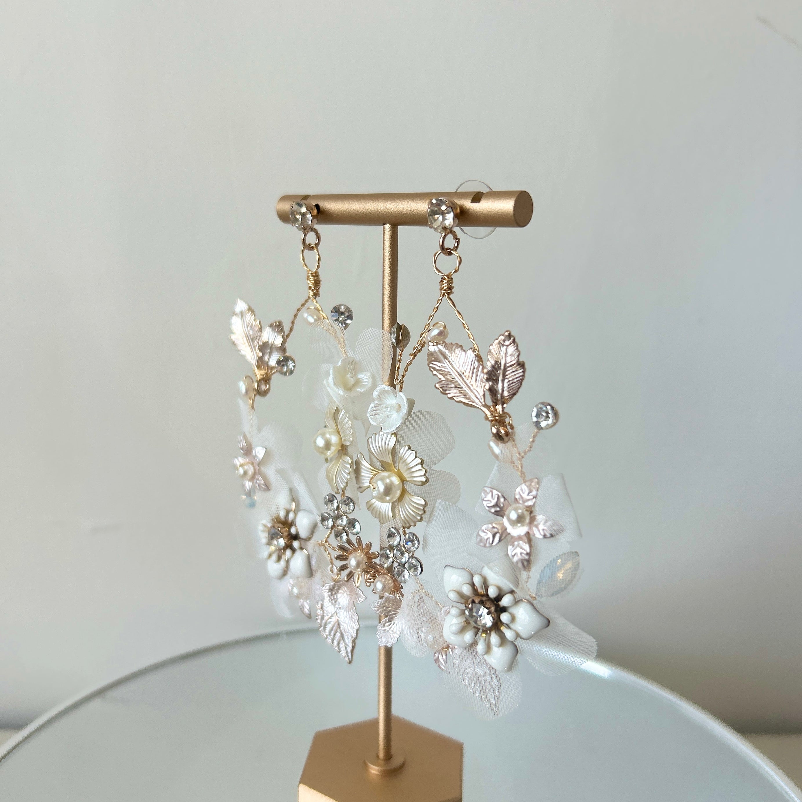 Pair of floral earrings on a gold stand against a light background