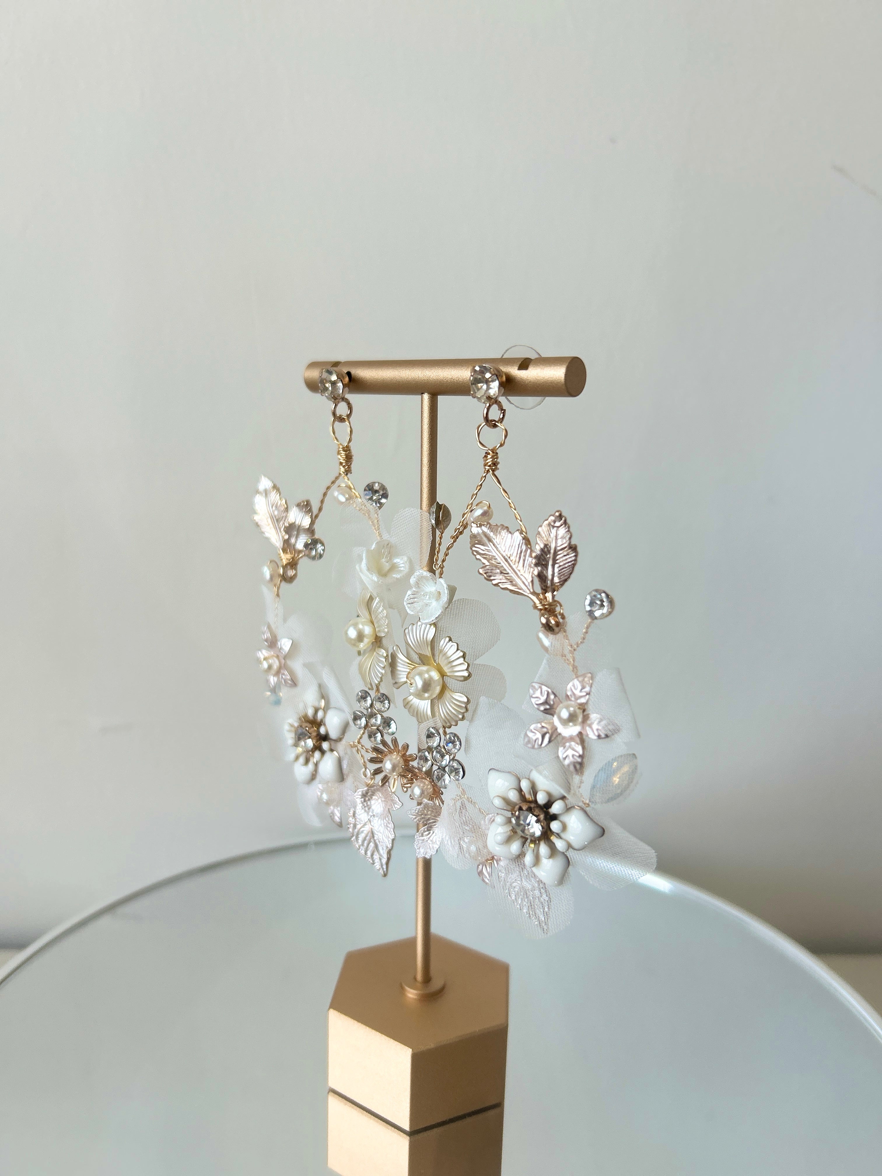 Pair of floral earrings on a gold stand against a light background