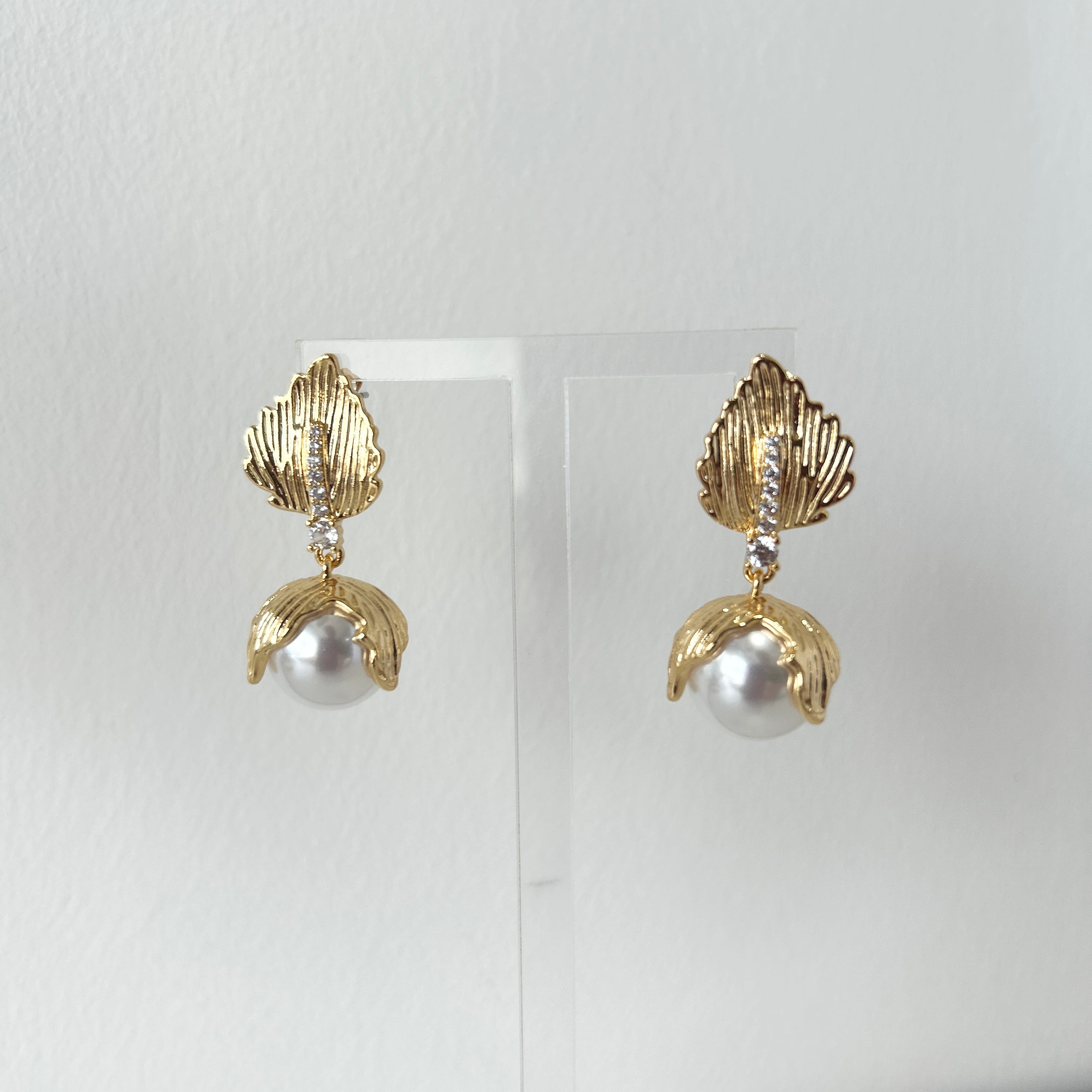 Gold earrings with pearls on a white background