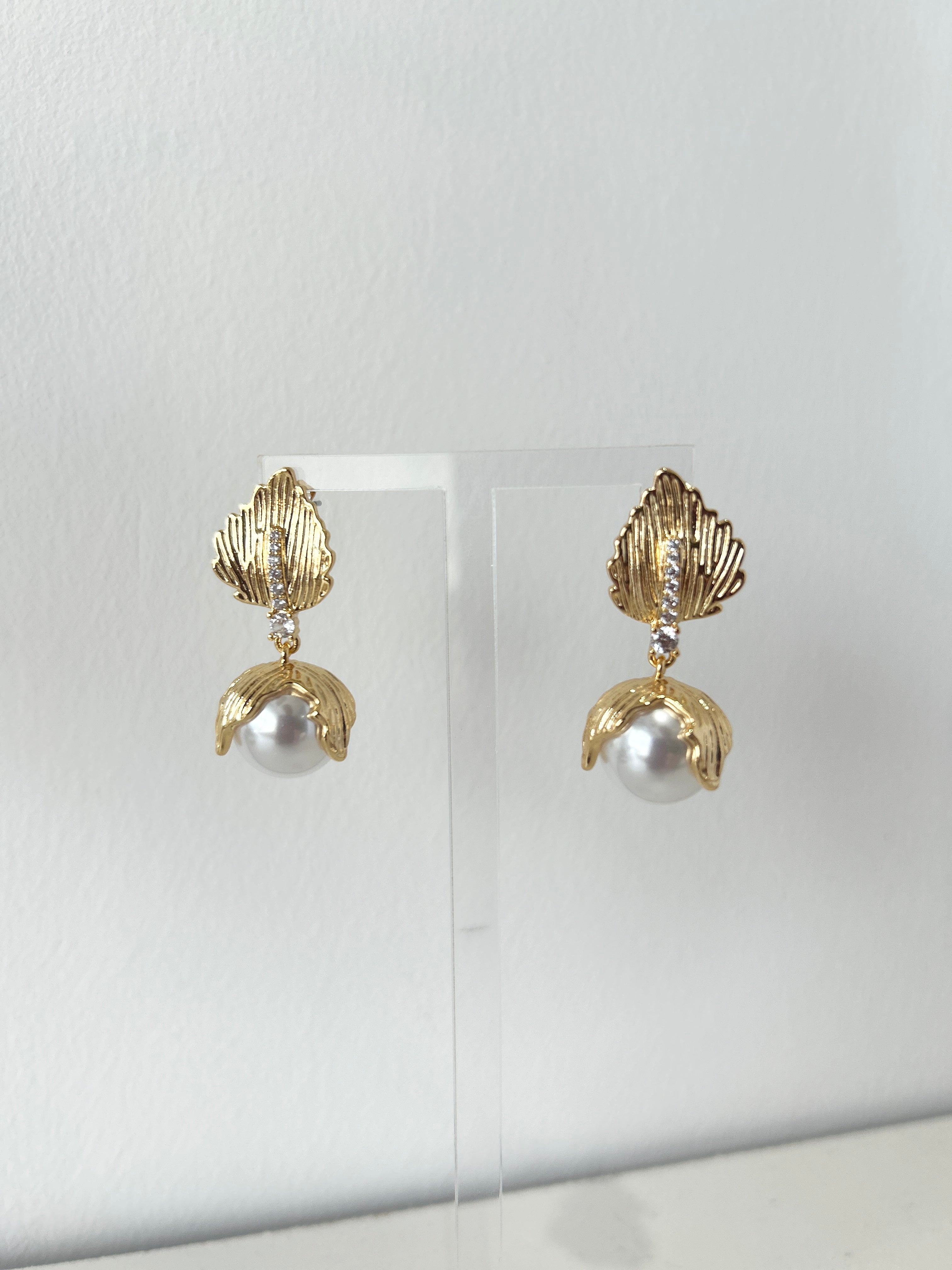 Gold earrings with pearls on a white background