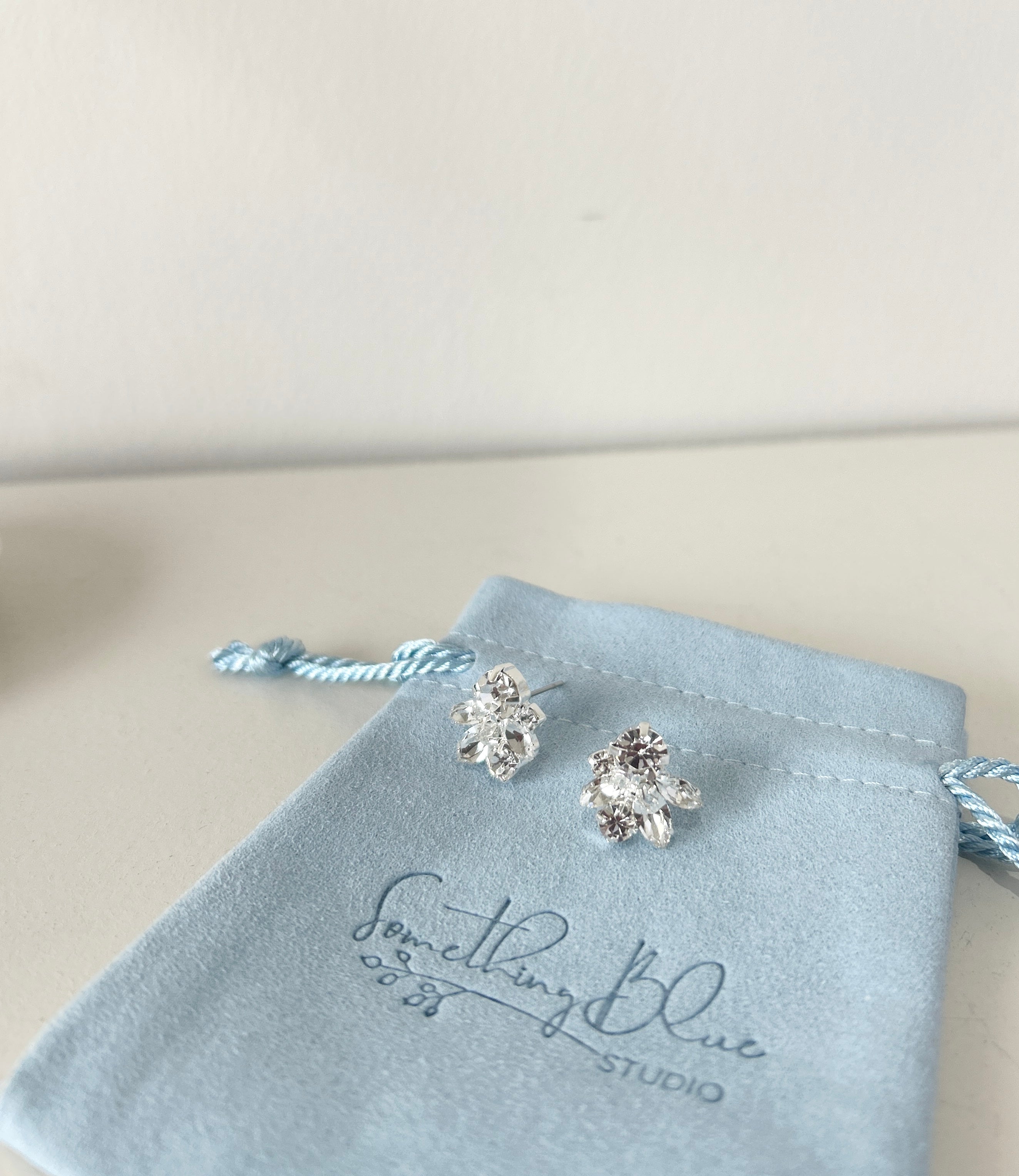 Pair of leaf shaped earrings on a Something Blue Studio branded pouch.
