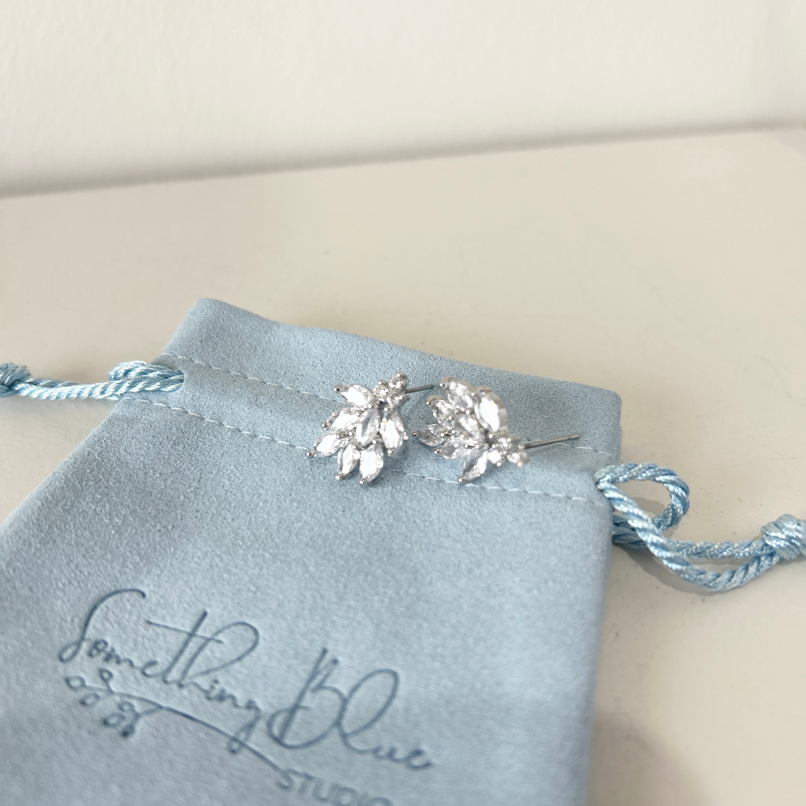 Crystal stud earrings on a Something Blue Studio branded pouch.