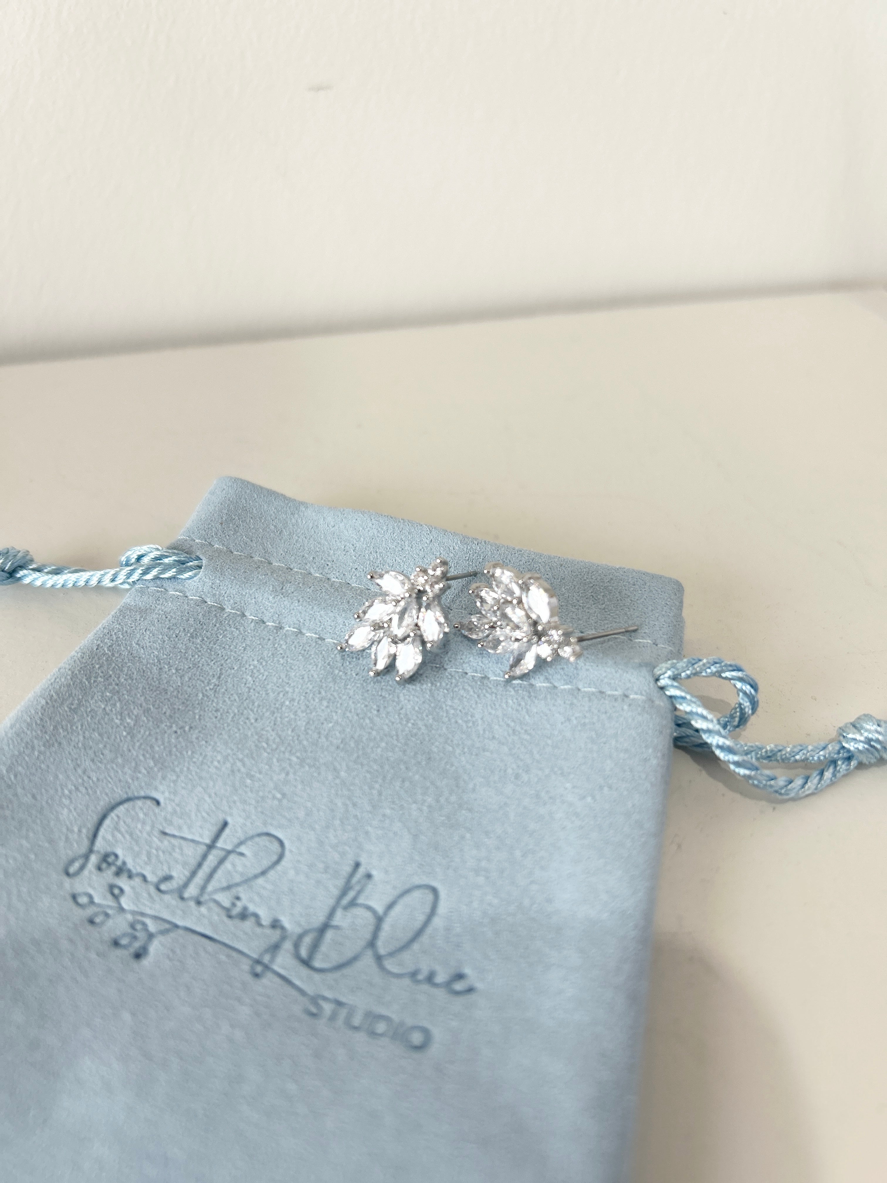 Crystal stud earrings on a Something Blue Studio branded pouch.