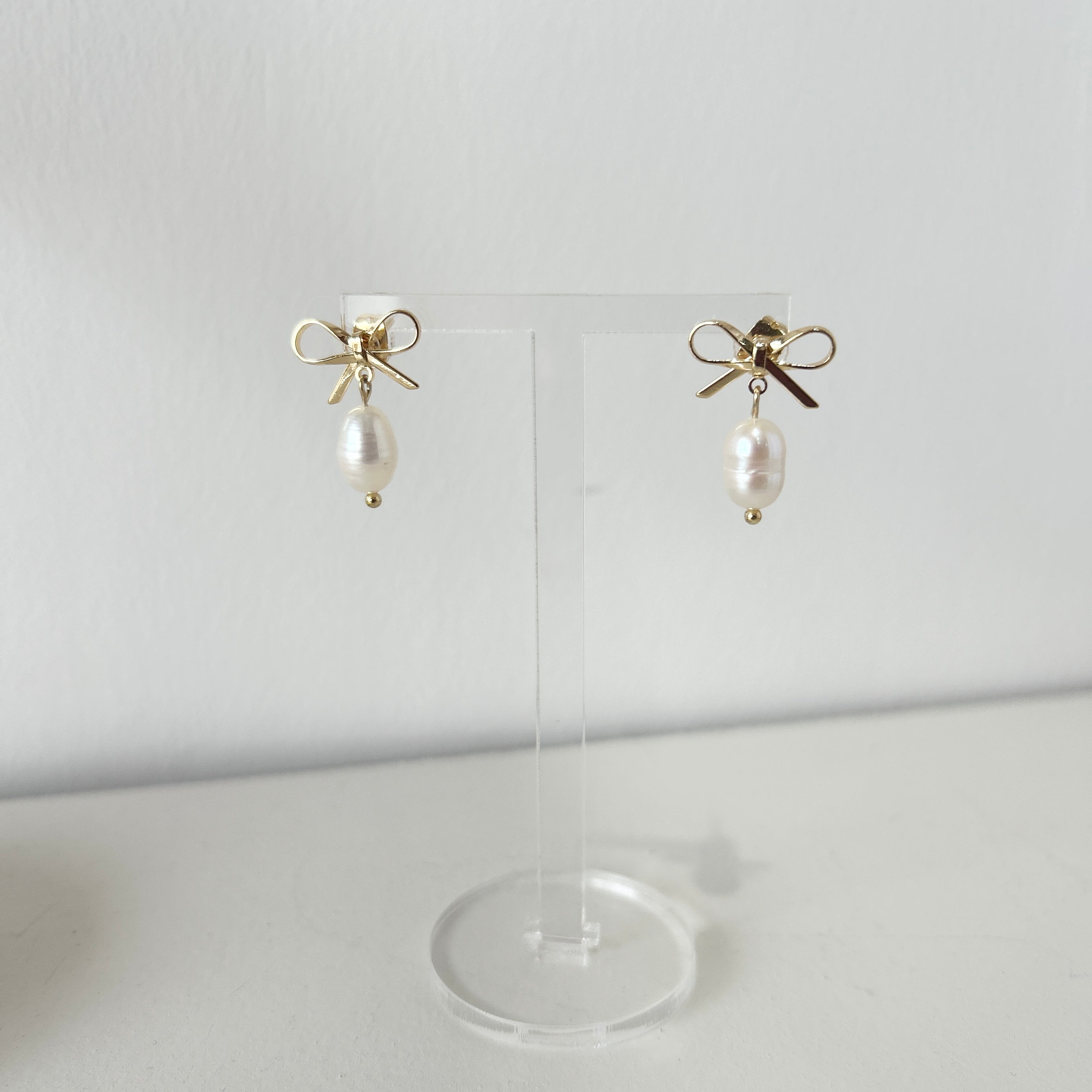 Pair of delicate gold bow earrings with a freshwater pearl drop