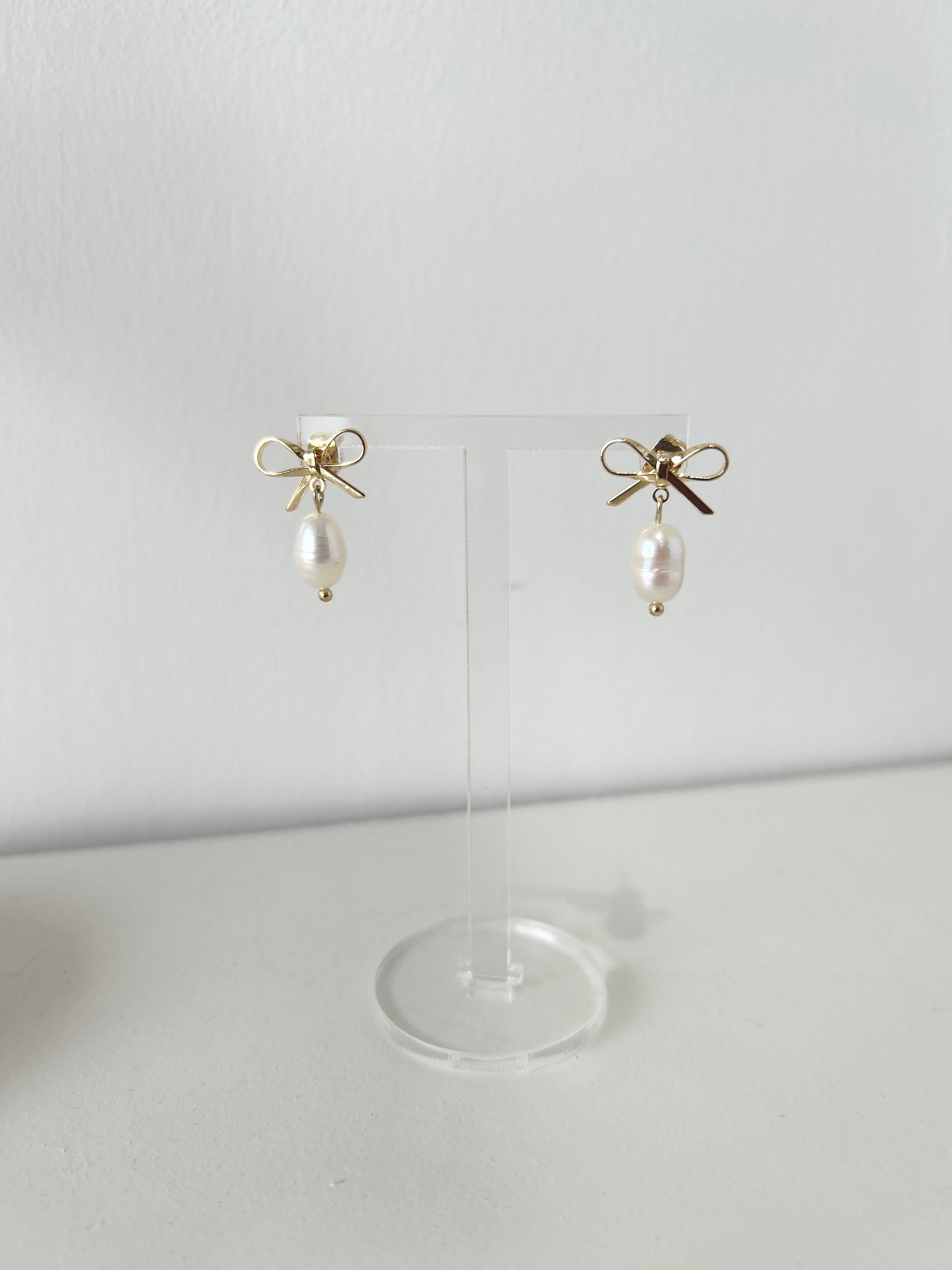 Pair of delicate gold bow earrings with a freshwater pearl drop
