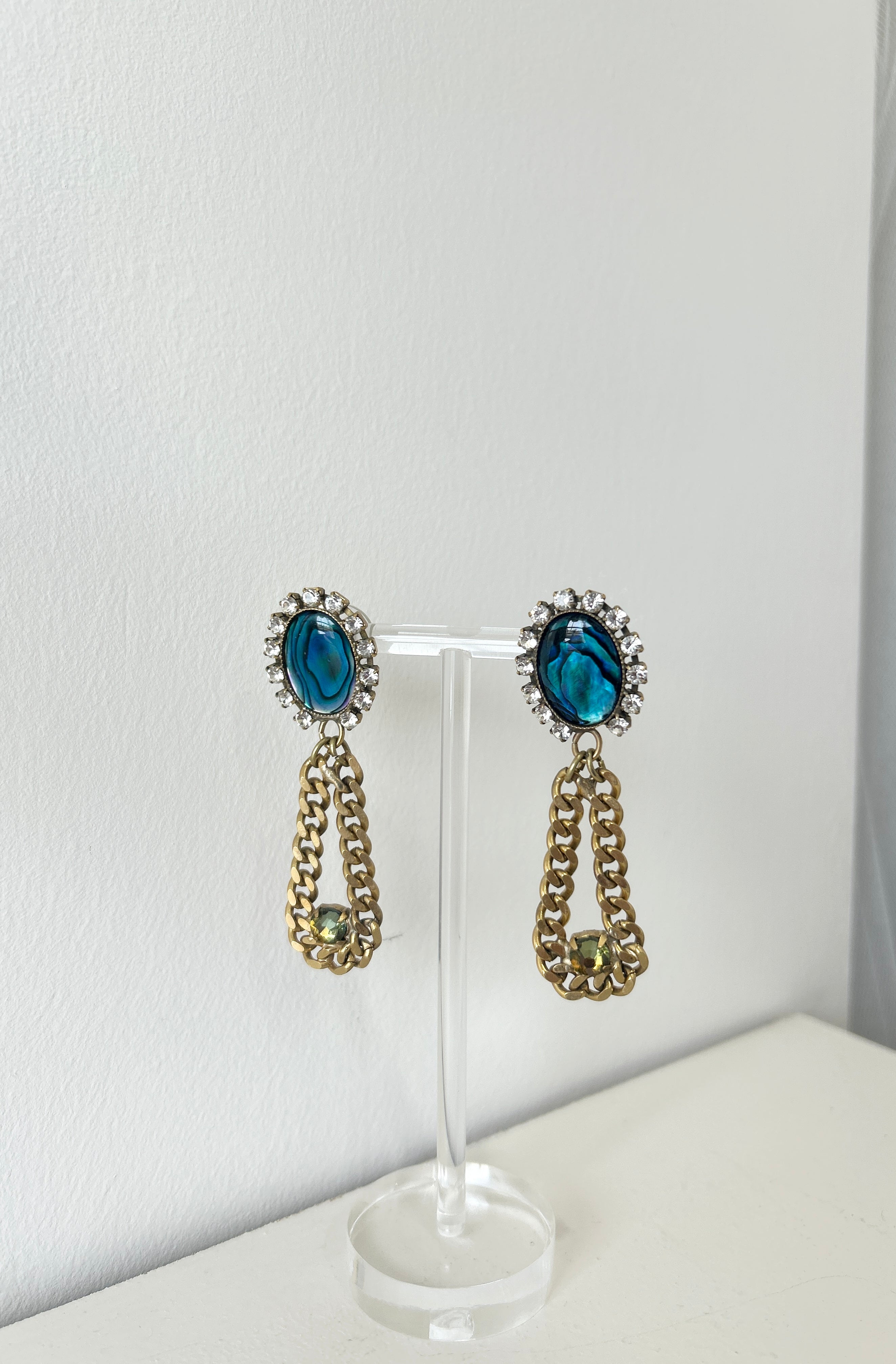 Pair of earrings with blue gemstones and gold chains on a white background