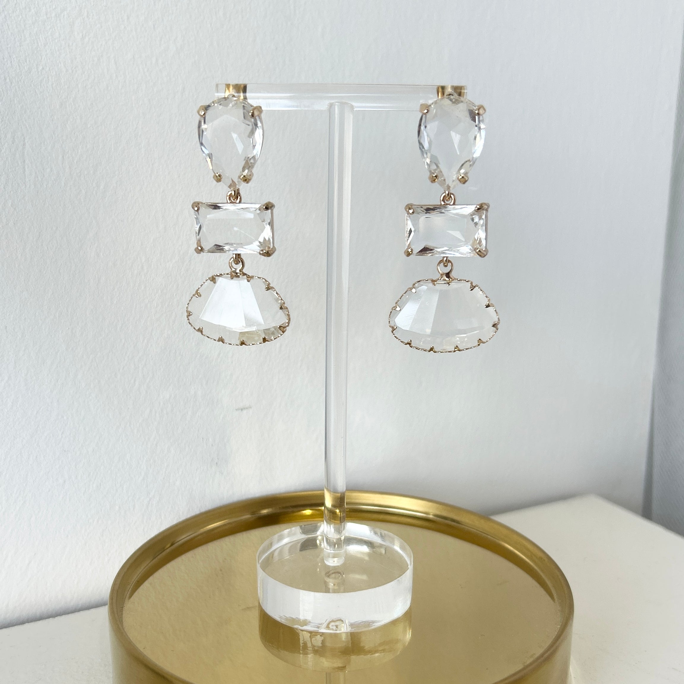 Pair of crystal earrings on a gold stand against a white background