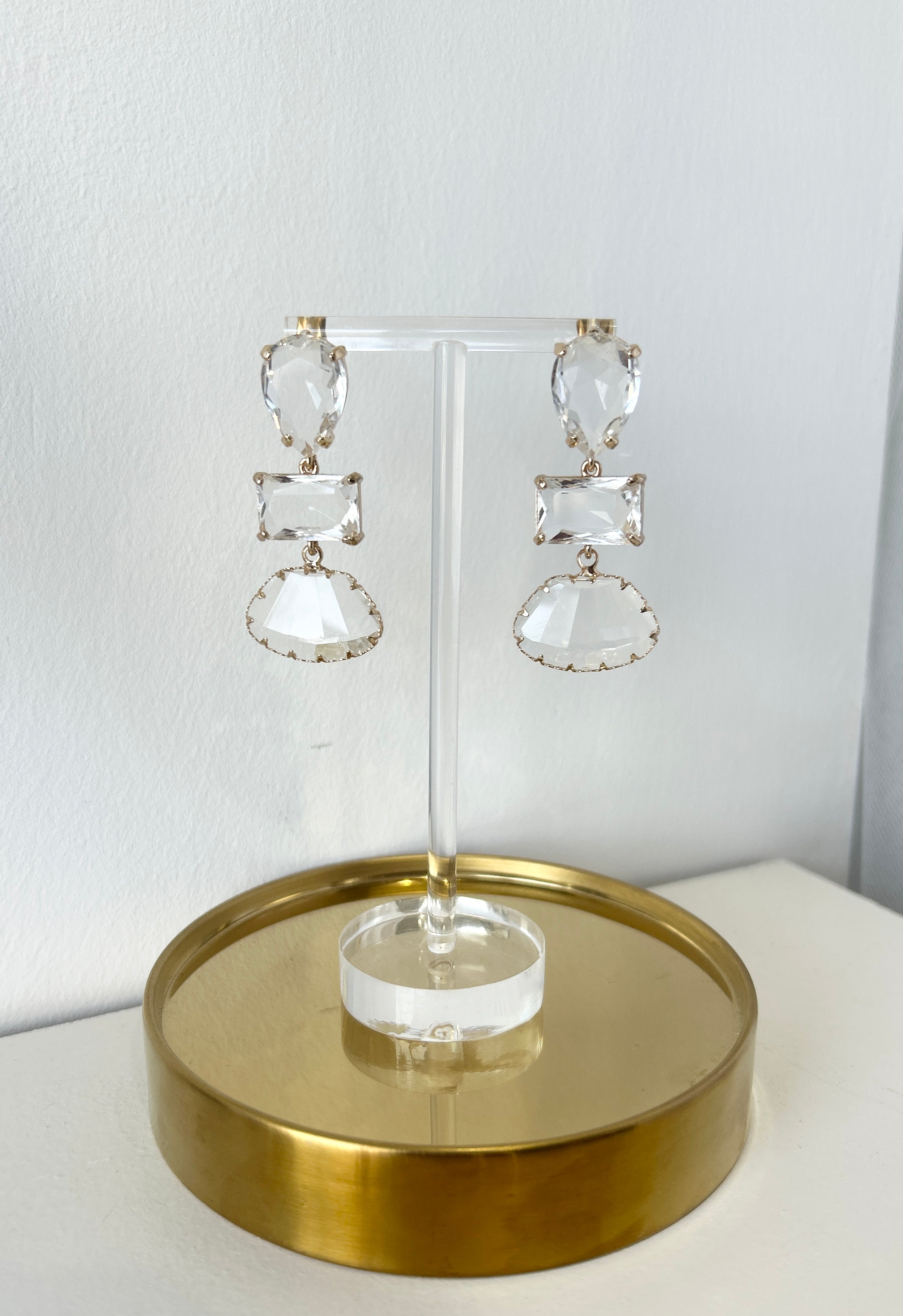 Pair of crystal earrings on a gold stand against a white background