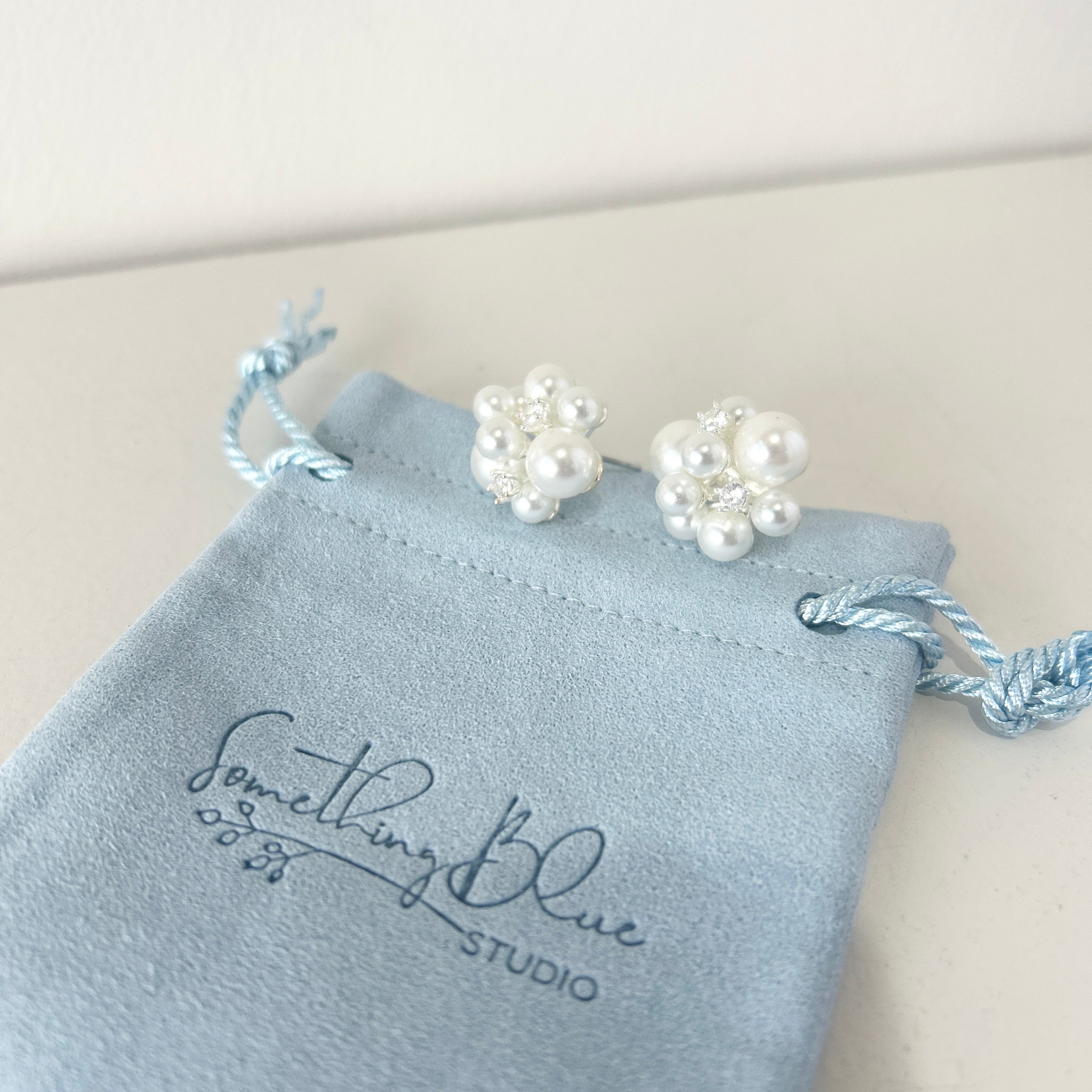 Pearl earrings on a Something Blue Studio branded pouch.