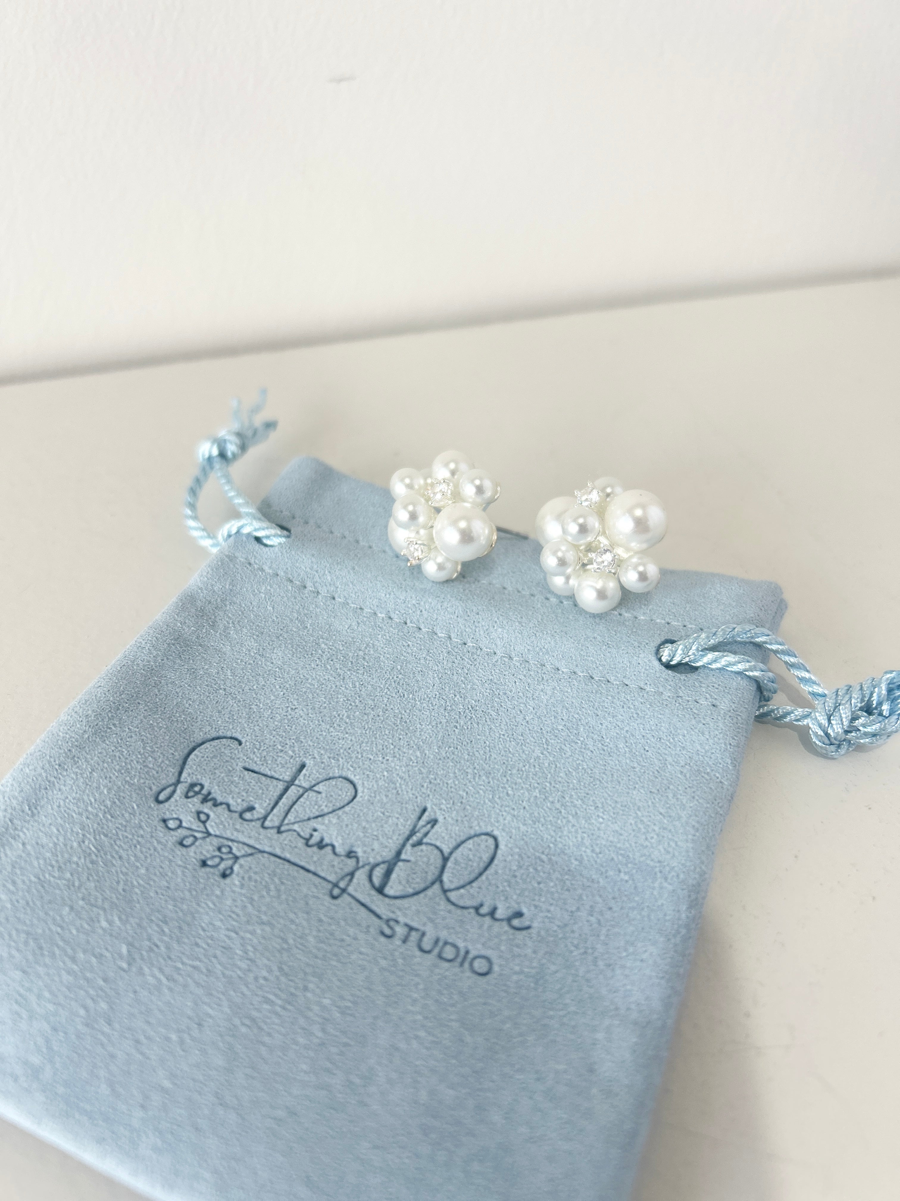 Pearl earrings on a Something Blue Studio branded pouch.