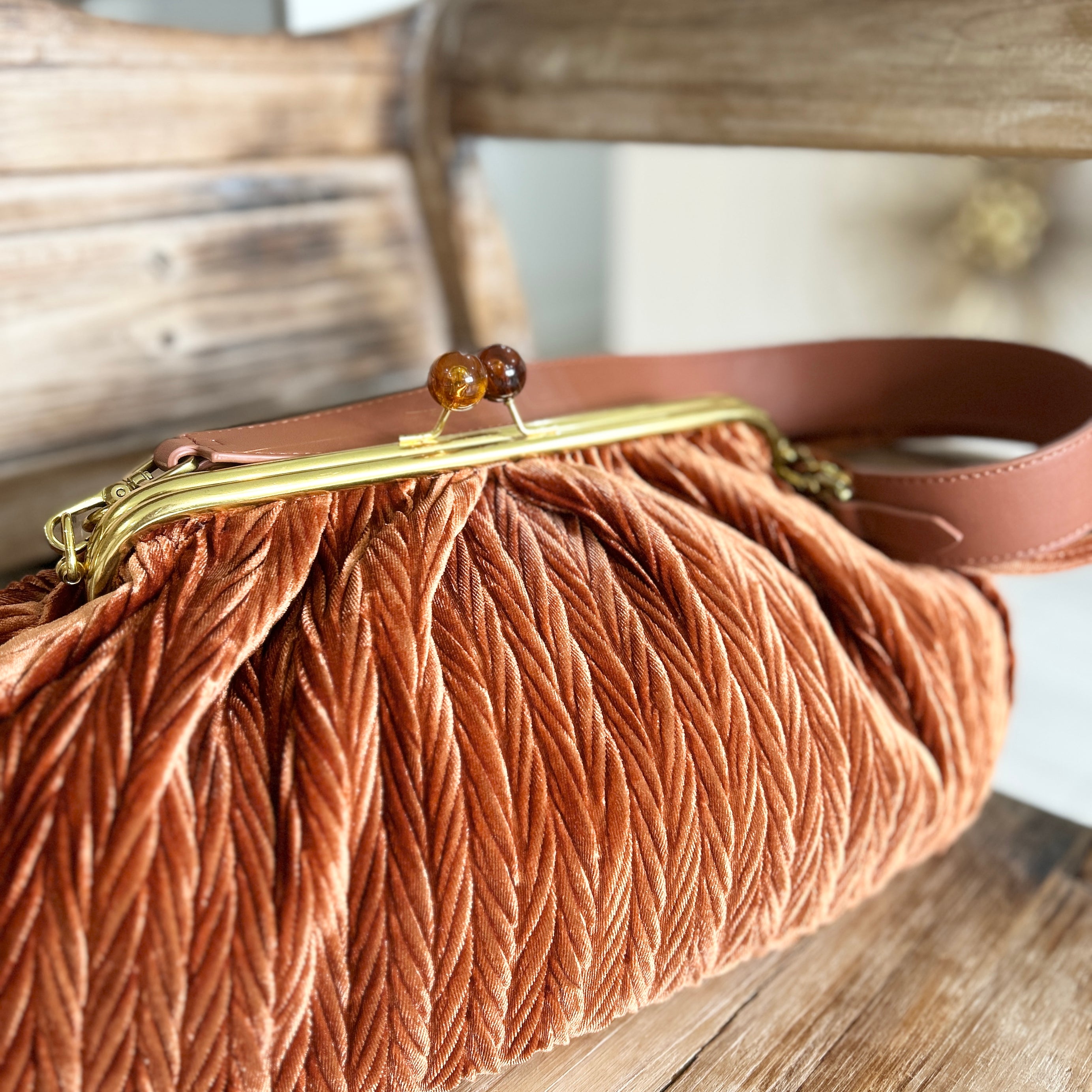 Brown vintage style brown velvet handbag with a gold snap clasp on a wooden surface