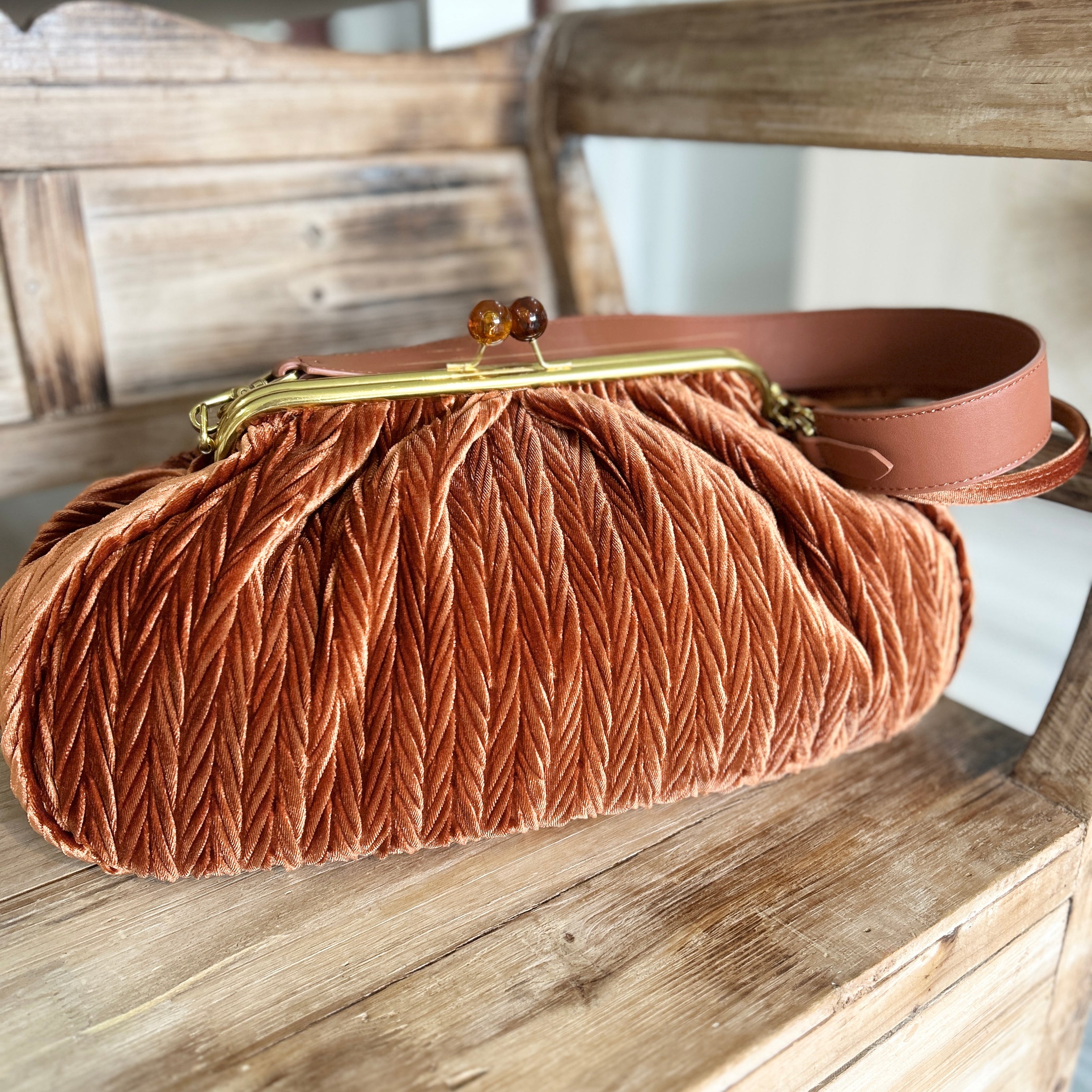 Brown vintage style brown velvet handbag with a gold snap clasp on a wooden surface