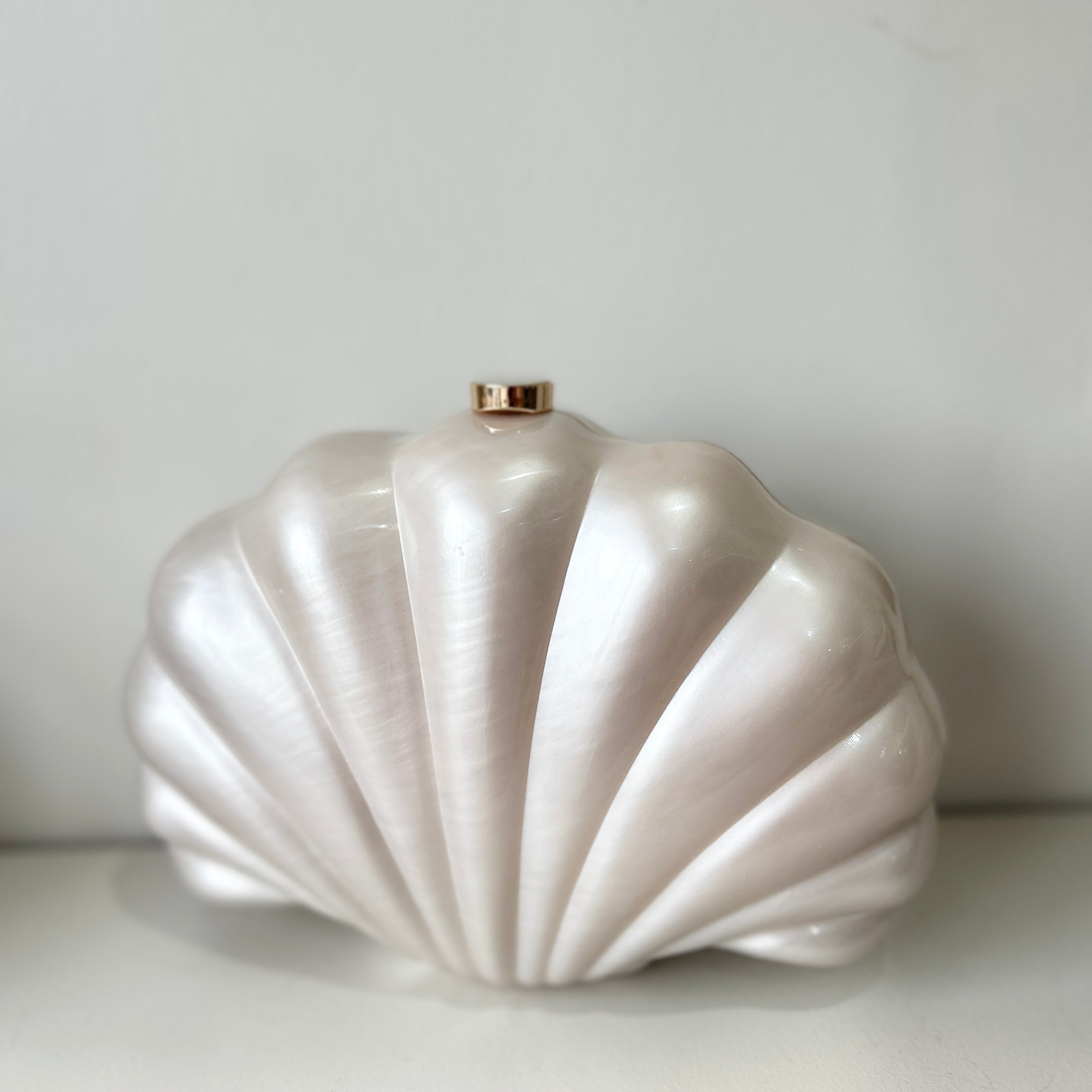 Shell-shaped white clutch bag on a light gray background