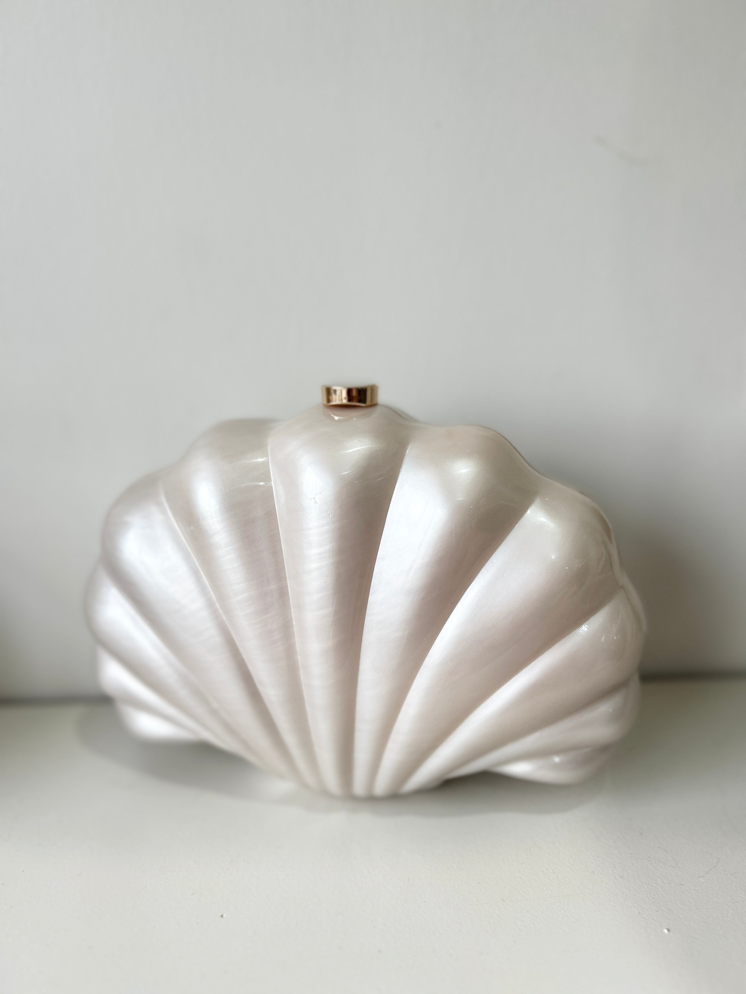Shell-shaped white clutch bag on a light gray background