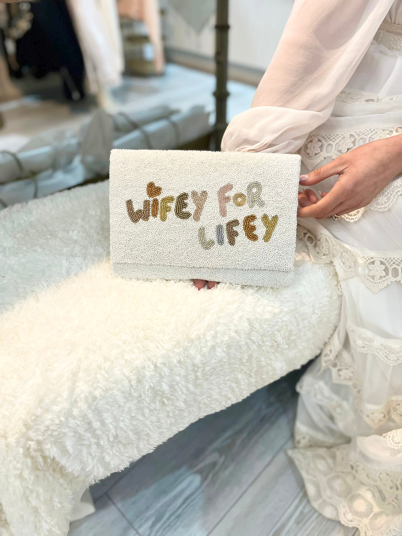 Lady holding a white bridal clutch with 'WIFEY FOR LIFELY' in beaded text