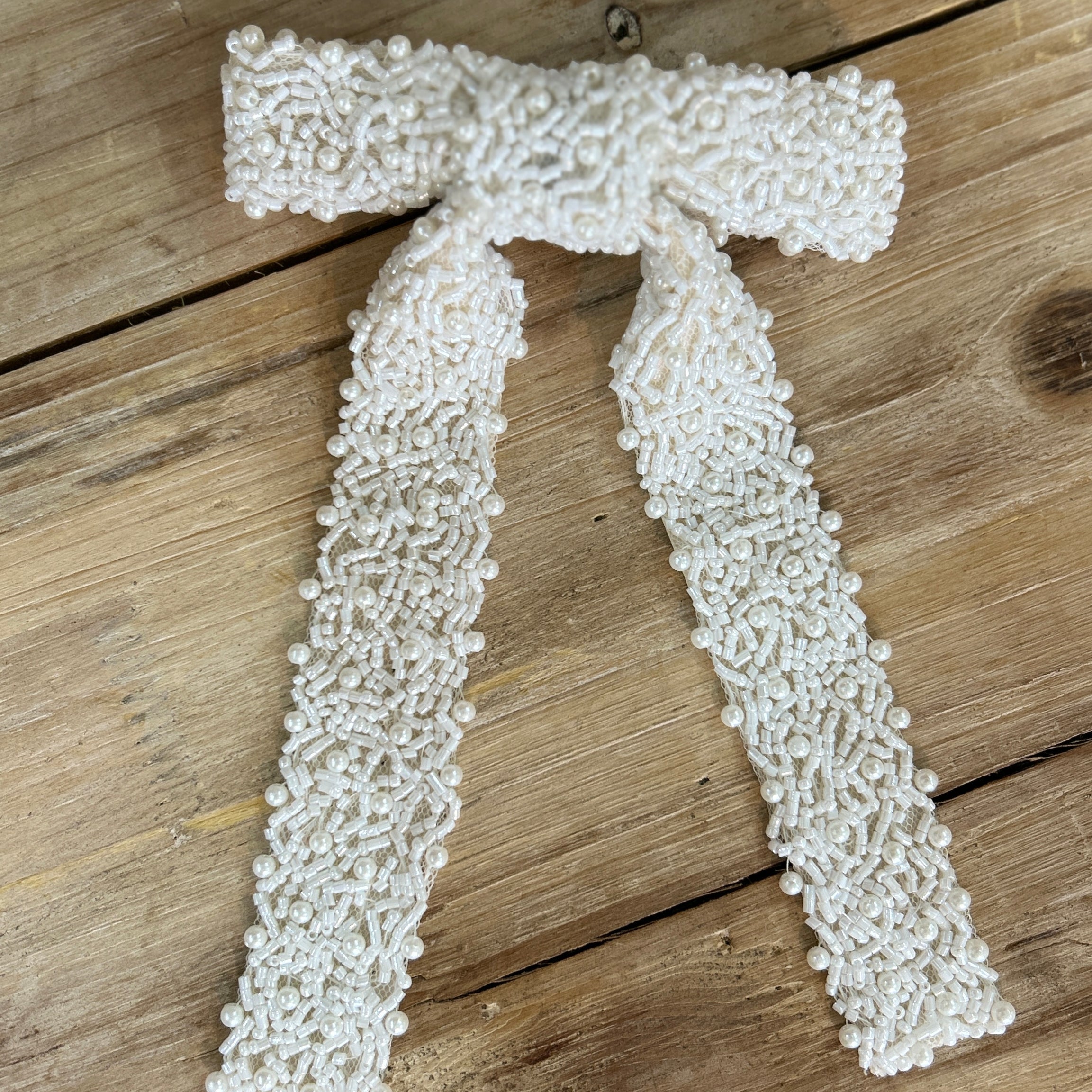 White beaded bridal hair bow on a wooden surface