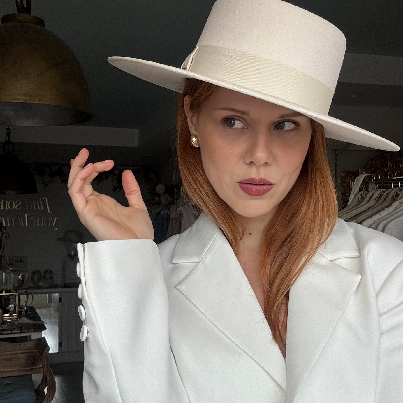 Woman wearing a white hat and coat in an indoor setting