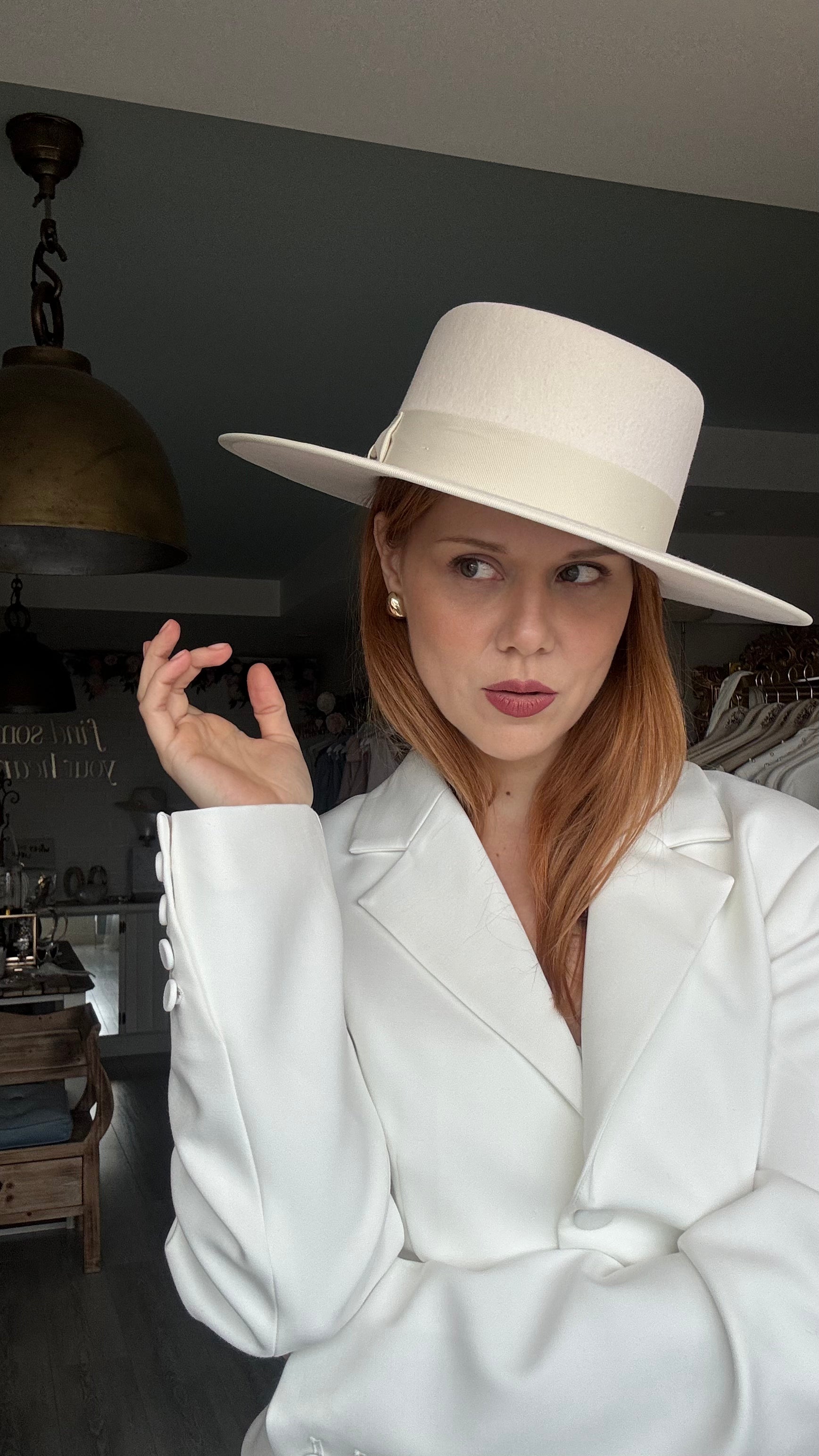 Woman wearing a white hat and coat in an indoor setting