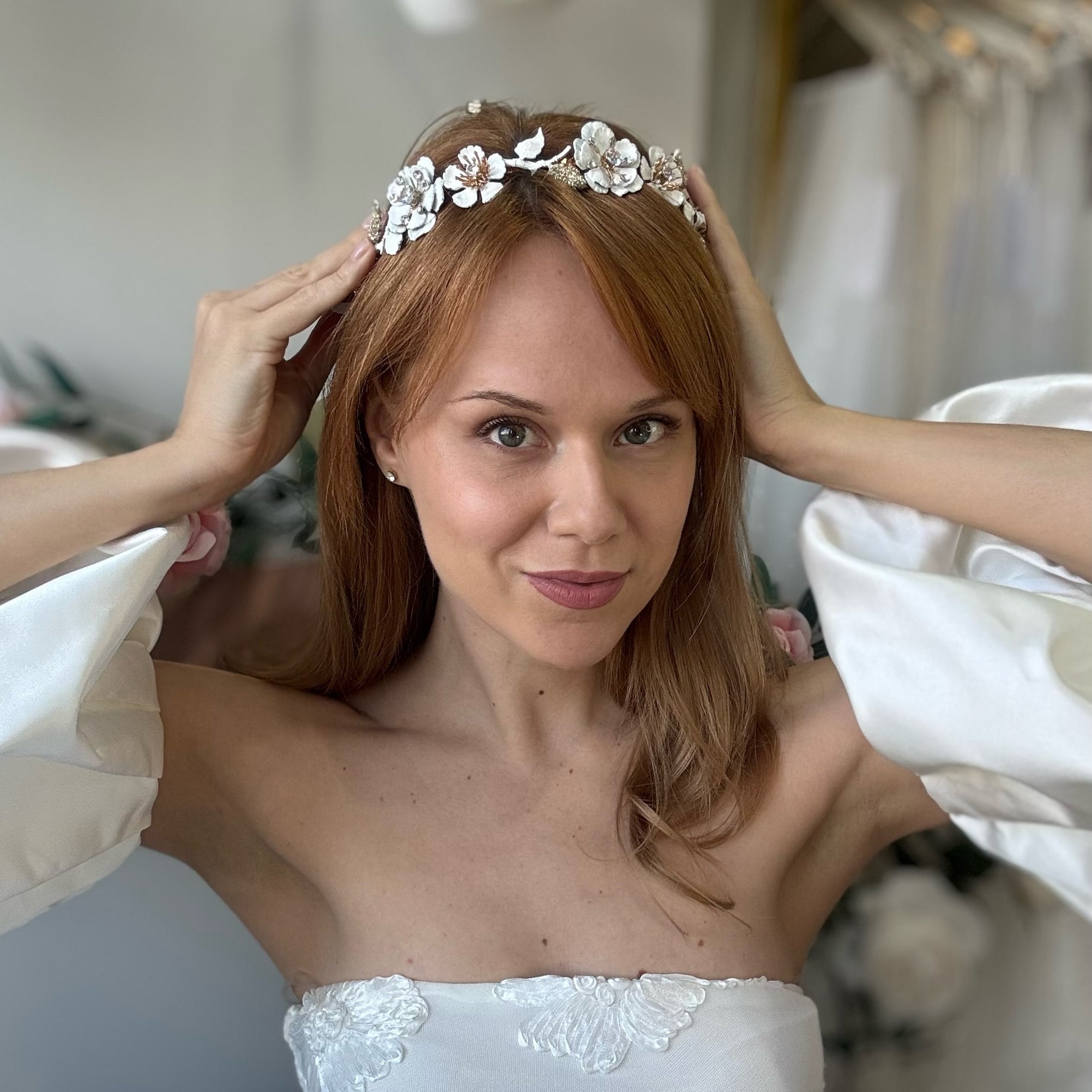 Woman wearing a floral headpiece and white dress, smiling at the camera.