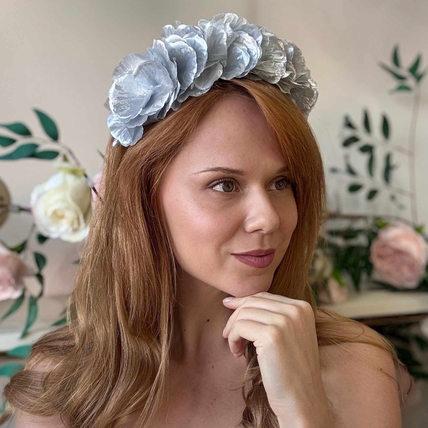 Woman wearing a silver statement floral headband with a blurred floral background