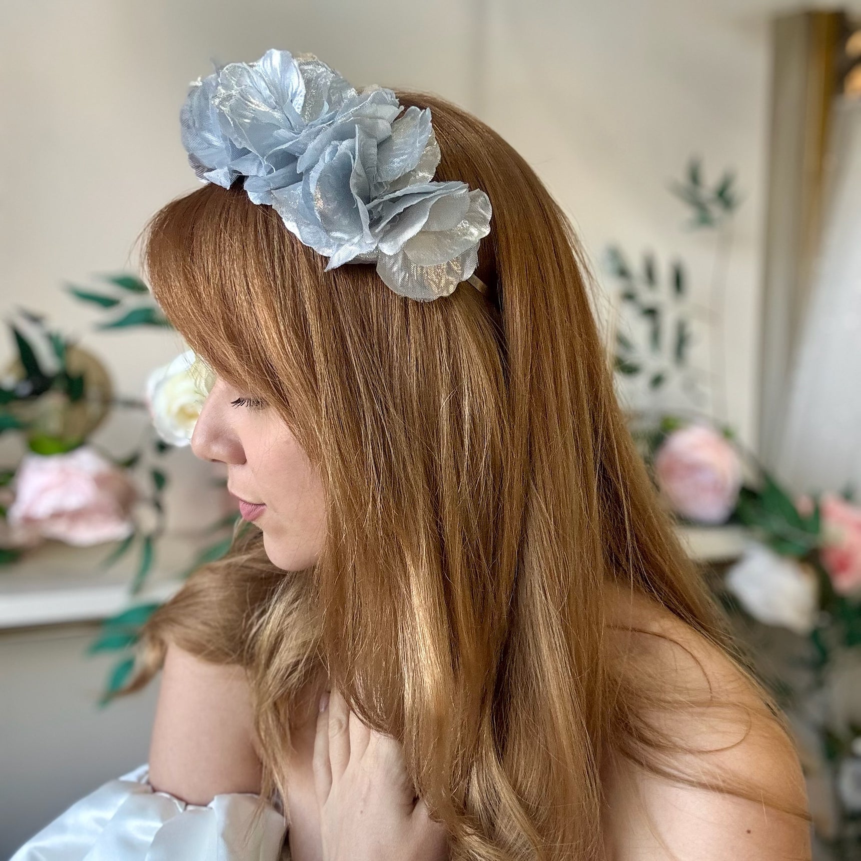 Woman wearing a silver statement floral headband with a blurred floral background