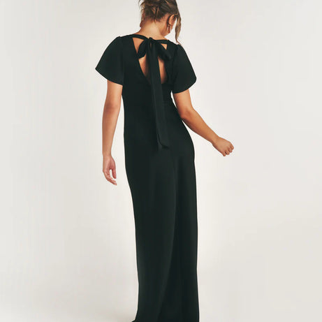 Woman wearing a black bridesmaid dress with a bow detail on a white background