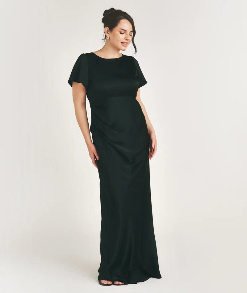 Woman wearing a black bridesmaid dress against a white background