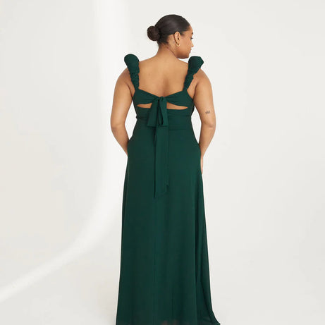 Woman wearing an emerald green chiffon gown with ruffled shoulders on a white background